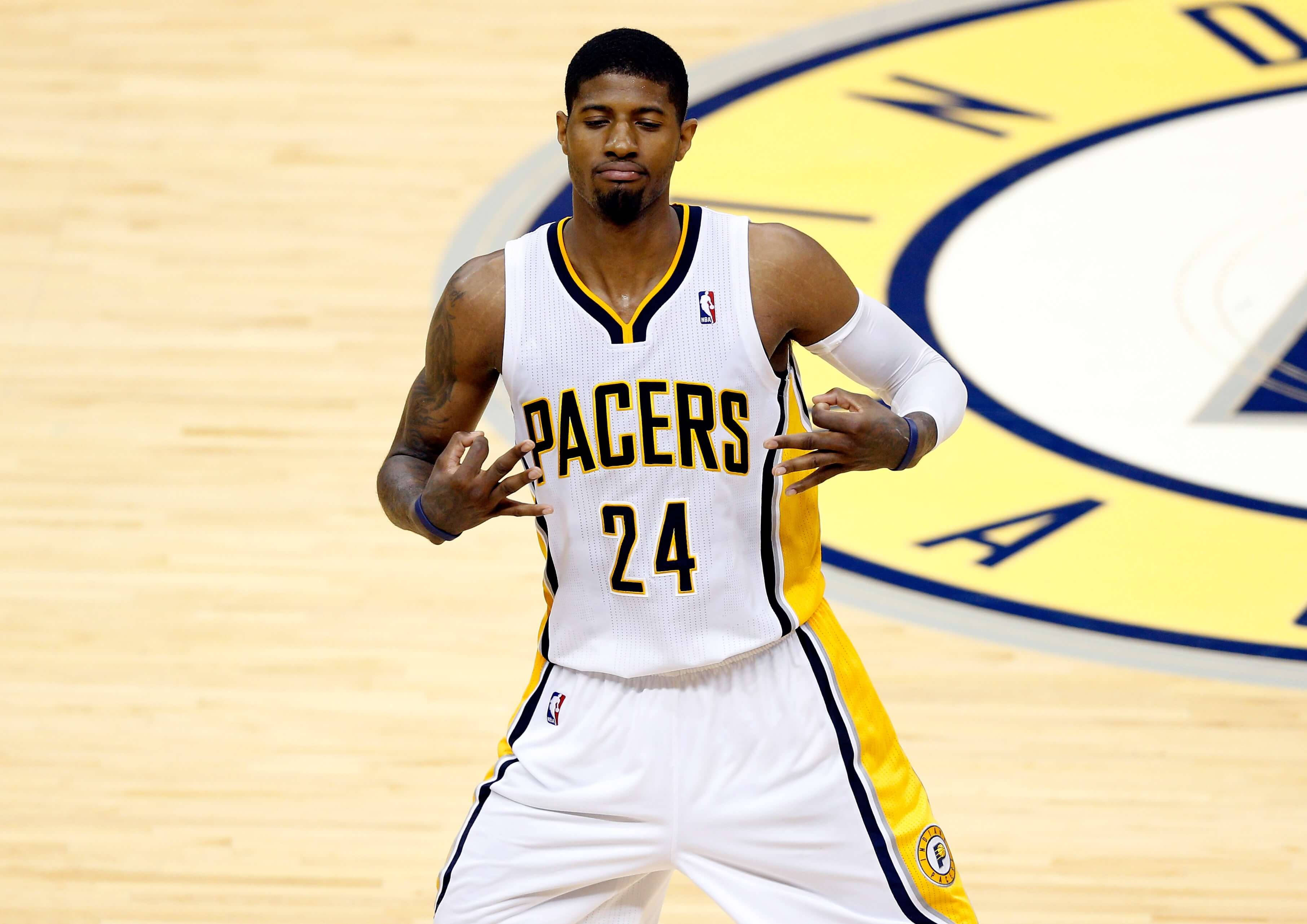 George 桌布 壁紙 — 籃球運動員 Paul George 身穿 Pacers 球衣在硬木球場上自信地做手勢。