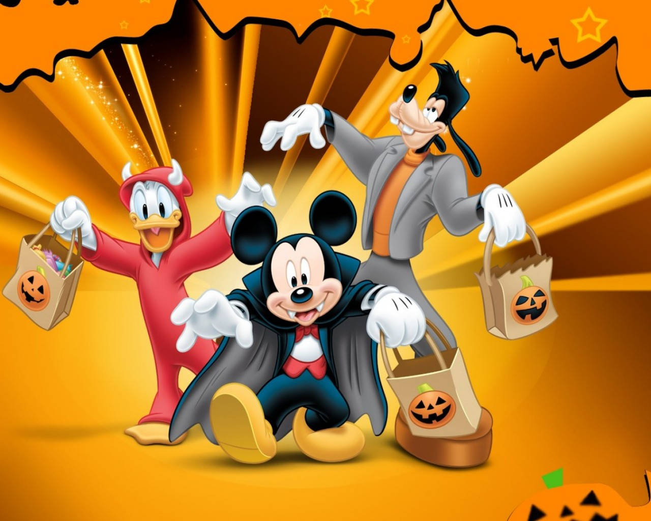 Cute Disney Halloween 桌布 壁紙 — 米奇、高飛和唐老鴨打扮成萬聖節角色，在燦爛的橙色背景前開心地拿著南瓜袋。