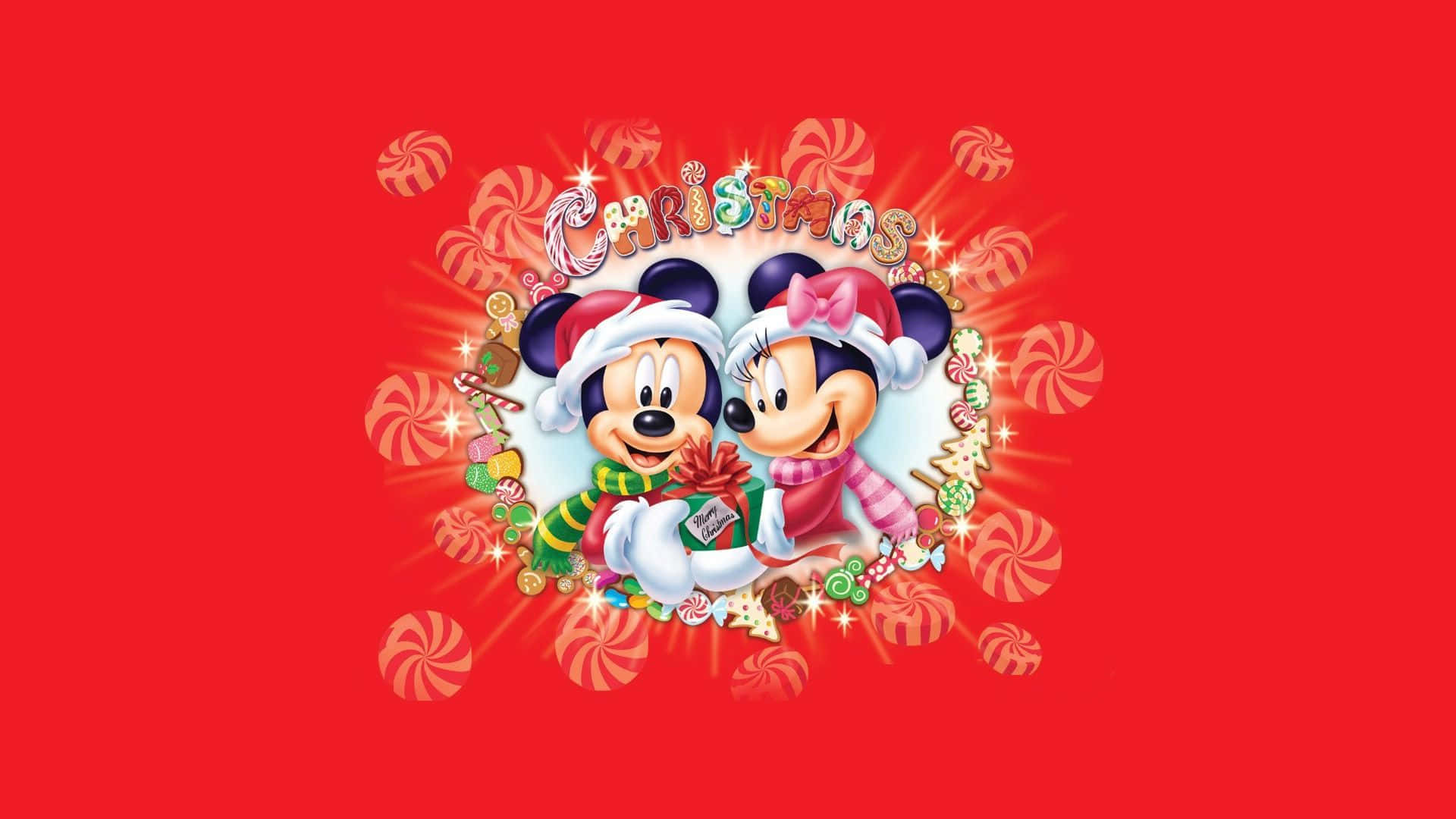 桌布 壁紙 — 米奇和米妮老鼠戴著節日聖誕帽，在充滿糖果手杖和閃光的鮮紅色背景上拿著一份禮物。