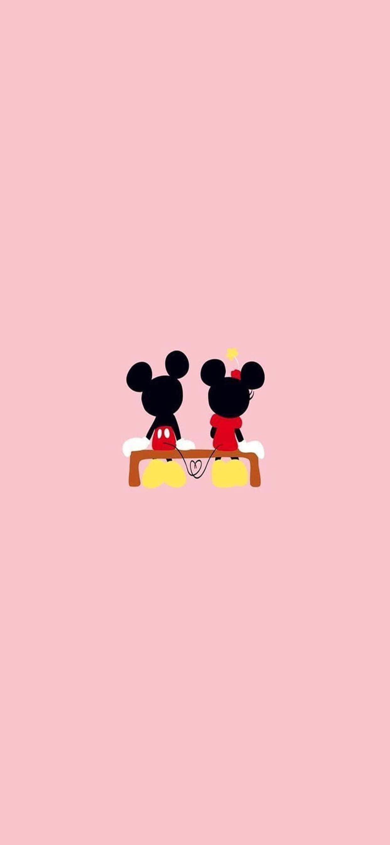 iPhone Xs Max Disney 桌布 壁紙 — 米奇和米妮老鼠背對背坐在長椅上，背景是柔和的粉紅色，上方有一個小心形。