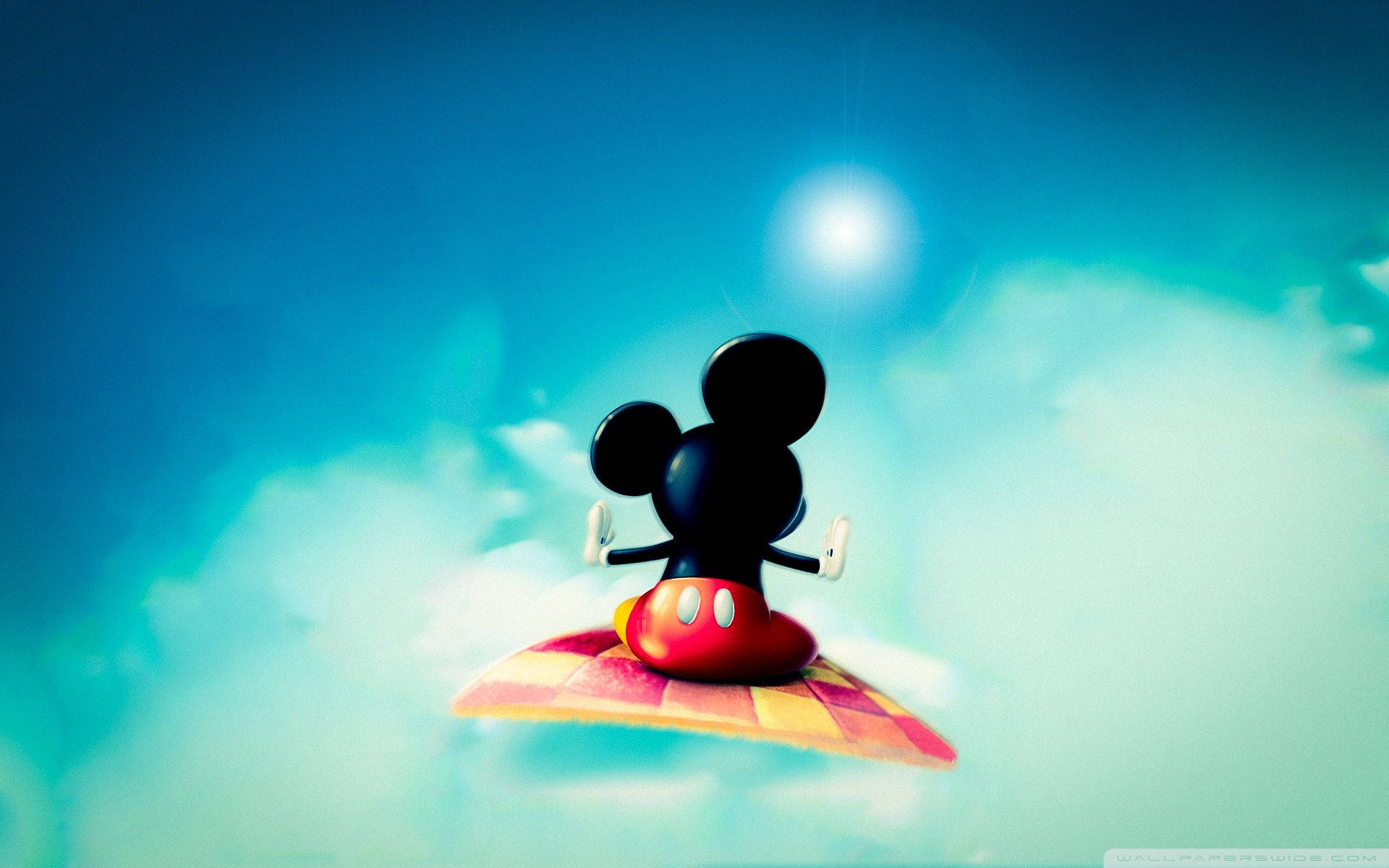 Mickey 桌布 壁紙 — 米奇老鼠在明亮的太陽下，平靜地坐在一塊漂浮在蓬鬆雲朵上的格子衝浪板上。