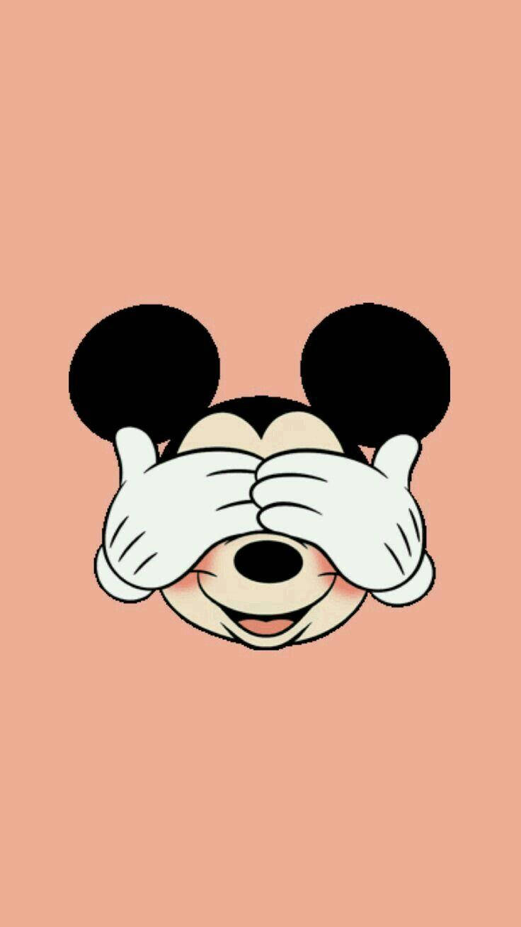 Mickey 桌布 壁紙 — 米奇老鼠用戴著手套的手頑皮地遮住眼睛，背景是純蜜桃色。