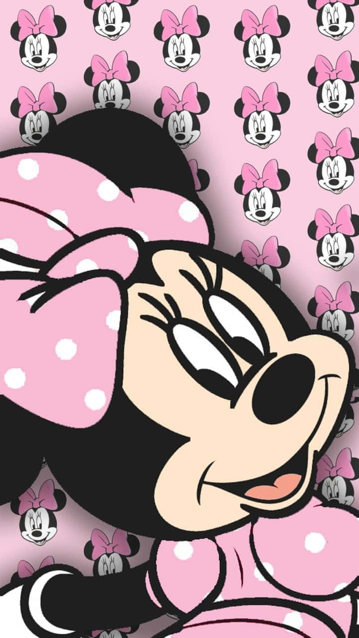 Minnie Mouse Pink 桌布 壁紙 — 米妮老鼠穿著粉紅色圓點服裝，在粉紅色背景上她的臉重複圖案前開心地微笑。