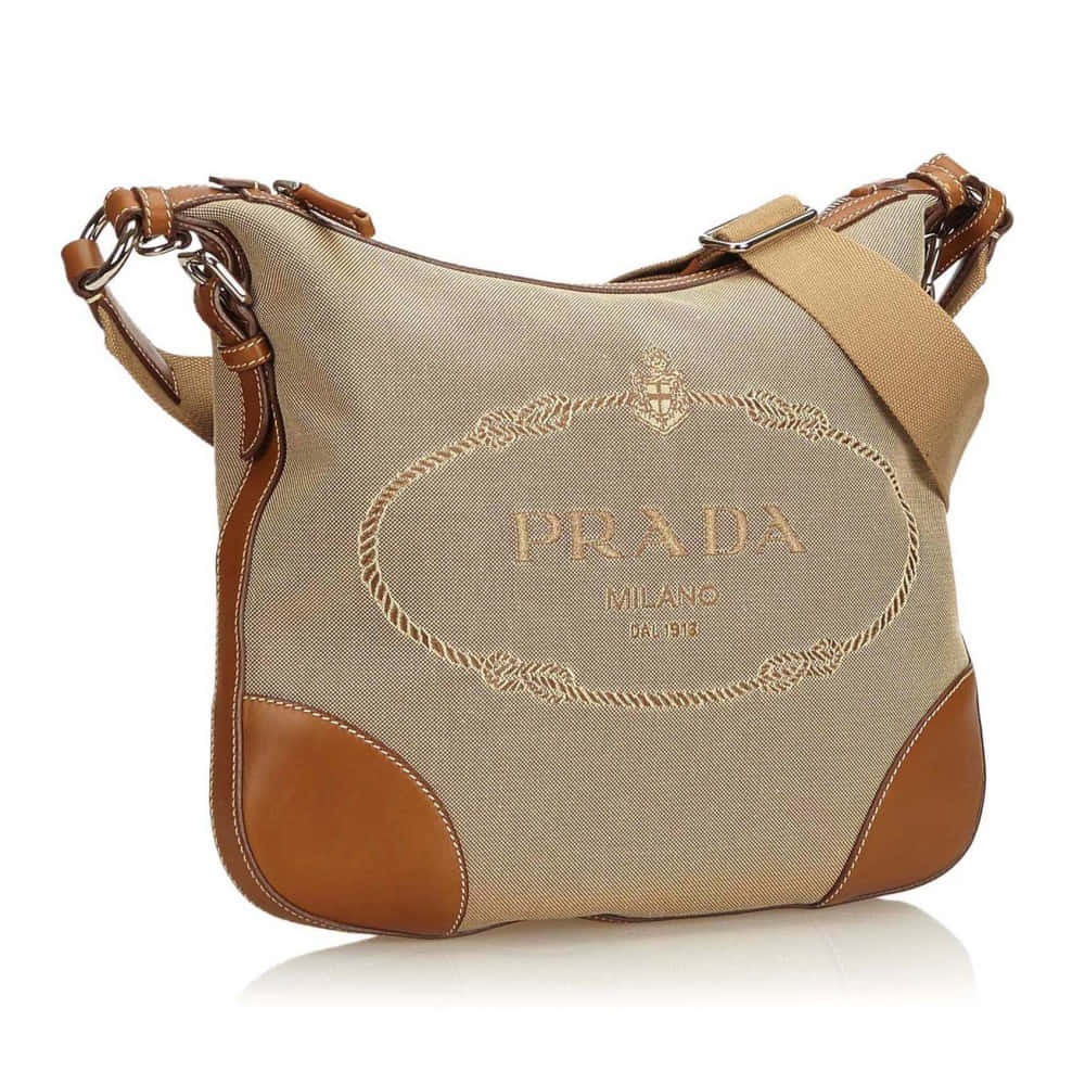 Prada 桌布 壁紙 — 米色Prada帆布肩背包，搭配棕色皮革飾邊和金色刺繡，白色背景。