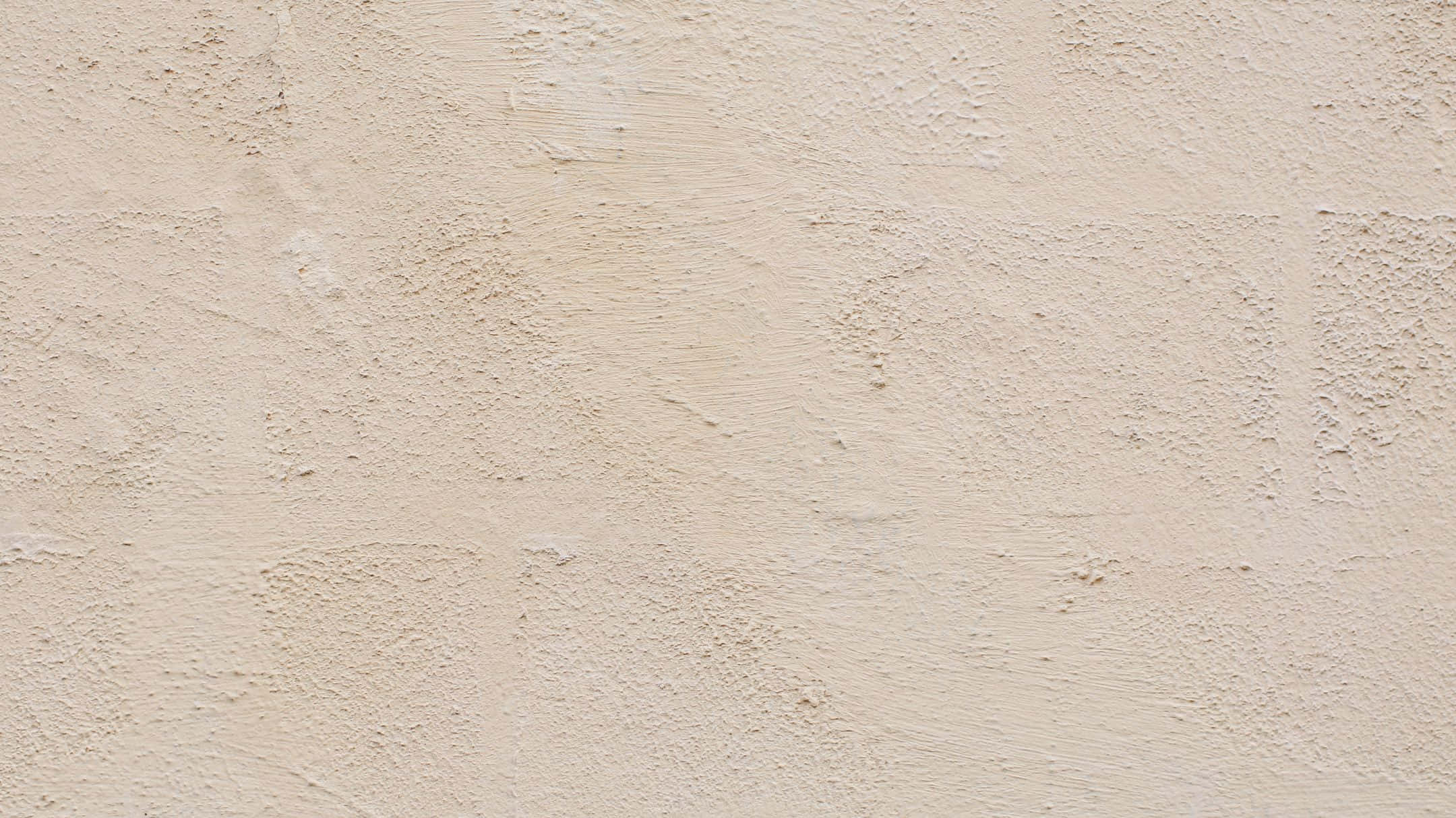 Wall Texture 桌布 壁紙 — 米色灰泥牆的特寫，帶有紋理斑塊和微妙的色調變化。