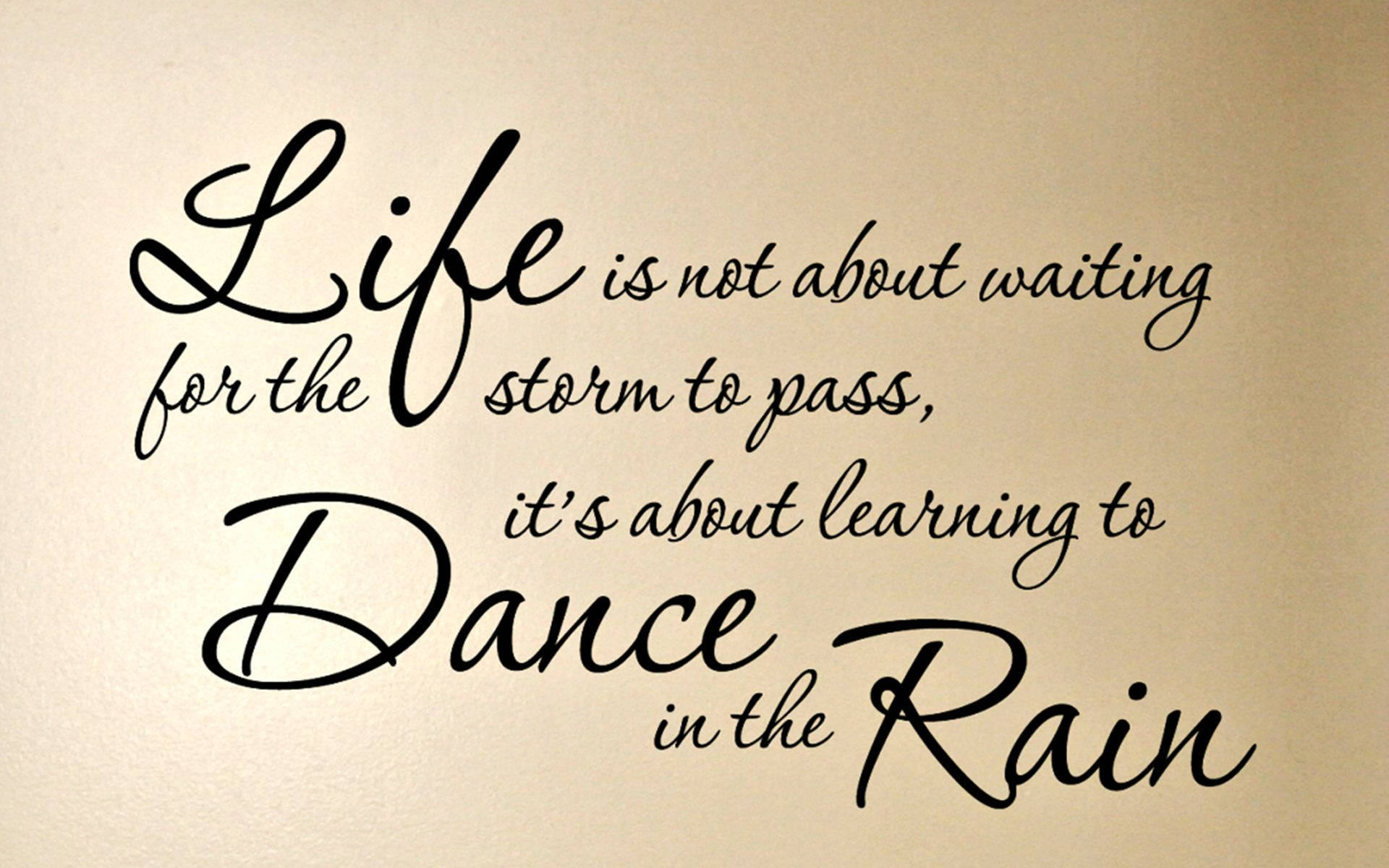 Inspirational Quotes 桌布 壁紙 — 米色牆上優雅的黑色草書牆貼寫著 'Life is not about waiting for the storm to pass it's about learning to Dance in the Rain'。