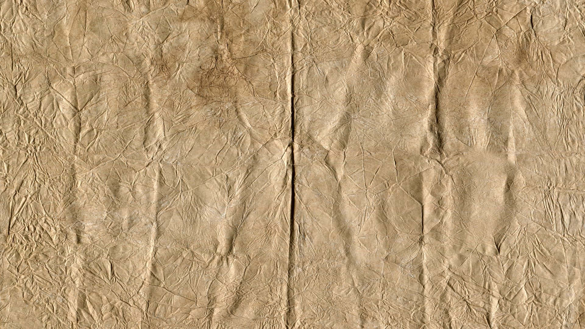 Old Paper Texture 桌布 壁紙 — 米色皺紙的特寫，帶有深摺痕和細微的棕色污漬，營造出質樸的紋理表面。