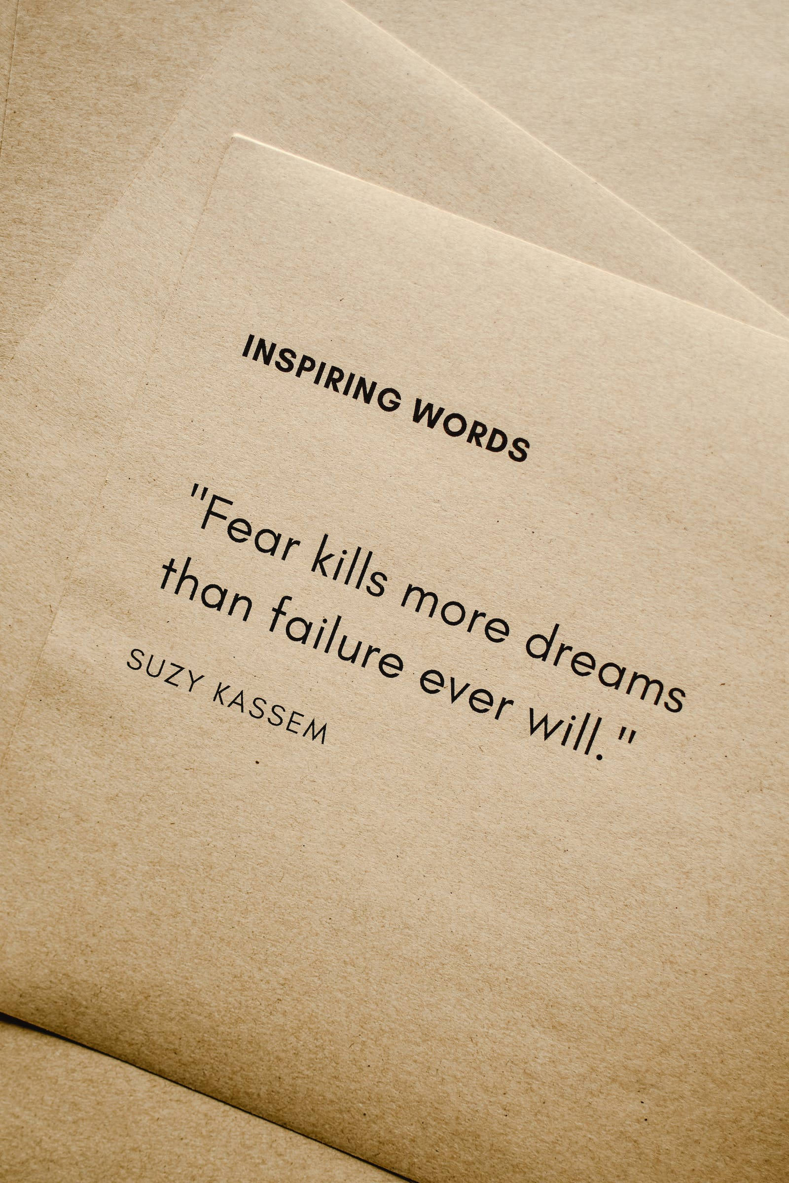 Motivational Quotes 桌布 壁紙 — 米色紙張的特寫，上面有黑色文字寫著 Suzy Kassem 的 'Fear kills more dreams than failure ever will'。