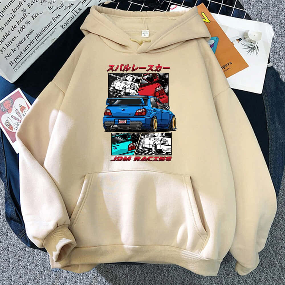 頭文字D 桌布 壁紙 — 米色連帽衫，帶有JDM賽車圖案，放在灰色紋理表面上，周圍散落著紙張和一本白色筆記本。