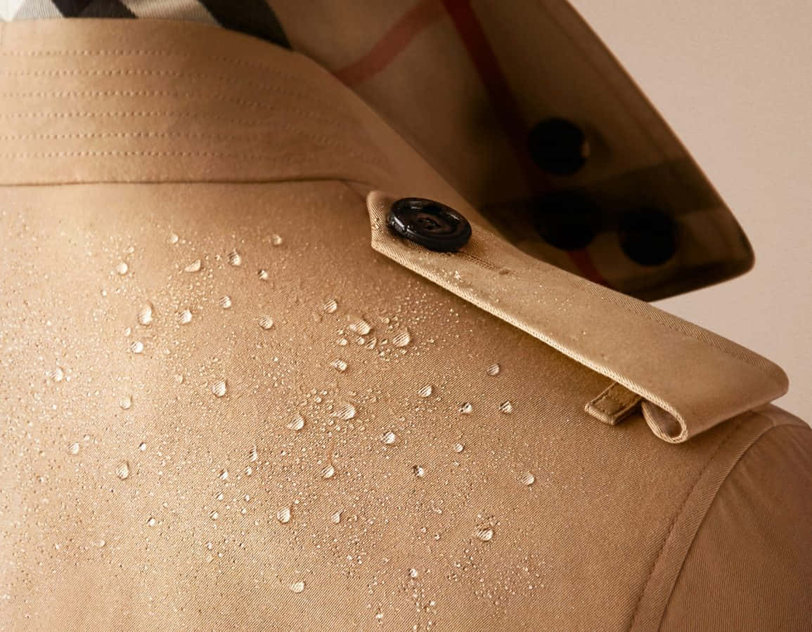 Burberry 桌布 壁紙 — 米色風衣的特寫，布料上凝結著水珠，黑色鈕扣細節。