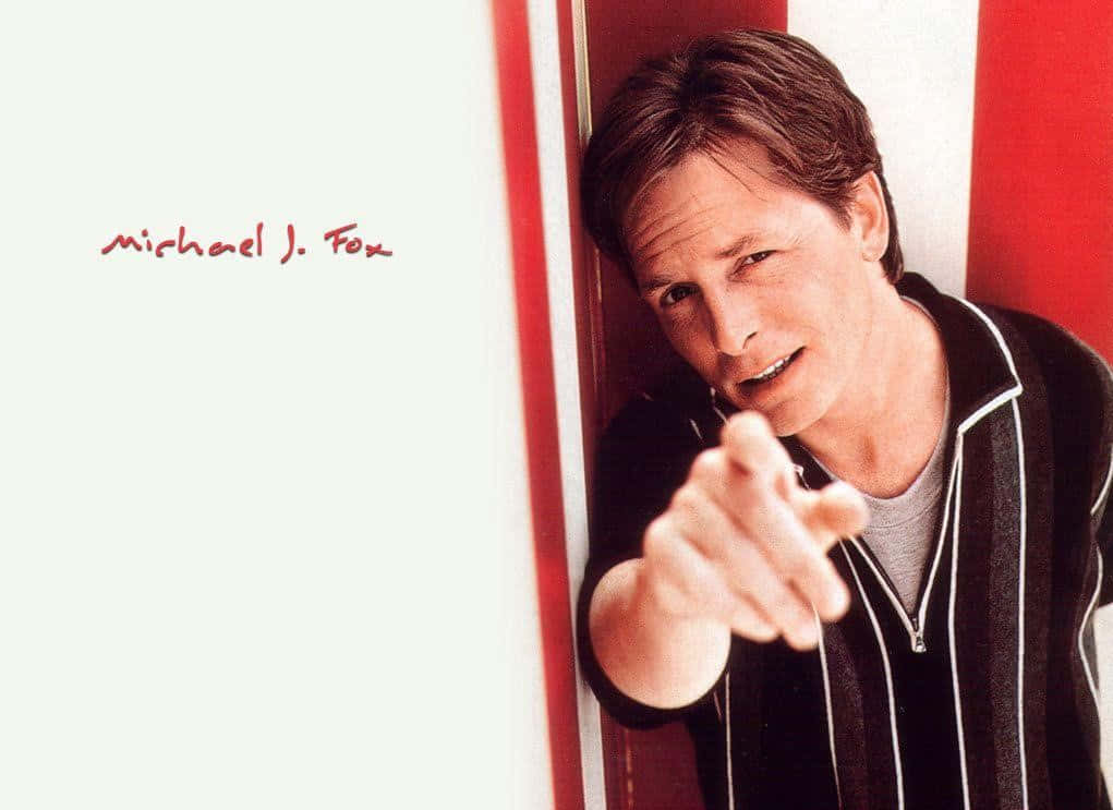 michael j fox 桌布 壁紙 — 米高·J·福克斯靠在紅白條紋牆上，帶著頑皮的笑容直接指向觀眾。