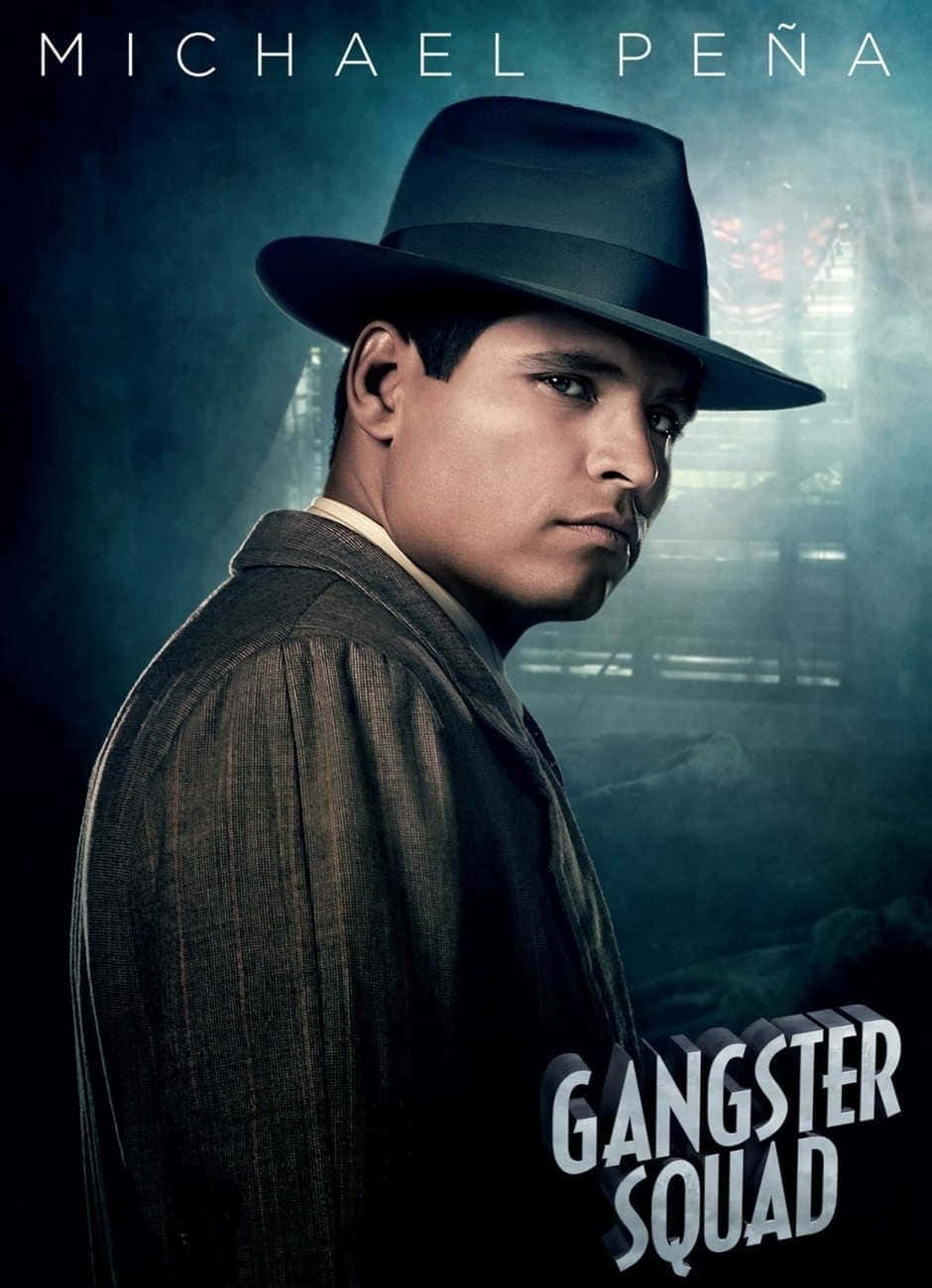 Michael Peña 桌布 壁紙 — 米高·潘納戴著軟呢帽和西裝，在煙霧瀰漫、燈光昏暗的城市背景下，凝視著帶有「Gangster Squad」字樣的畫面。