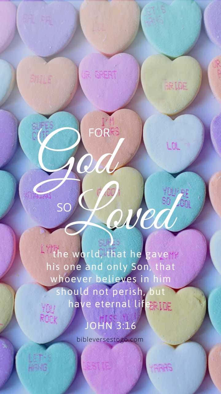 Girly Bible Verse 桌布 壁紙 — 粉彩心形糖果上寫有手寫訊息，形成色彩繽紛的背景，襯托出白色草書聖經經文，講述上帝的愛。