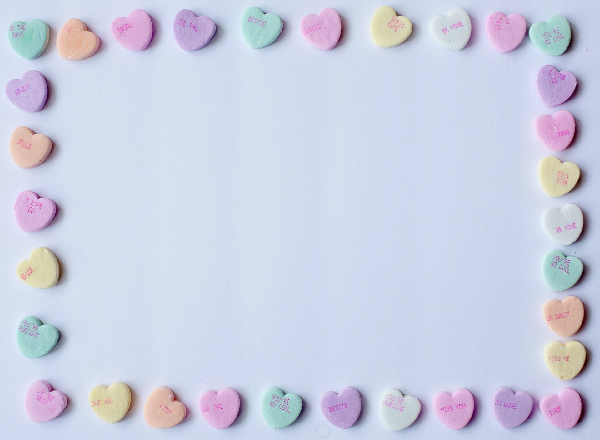 cute pastel colors 桌布 壁紙 — 粉彩心形糖果帶有甜蜜訊息，在純白背景上形成邊框。