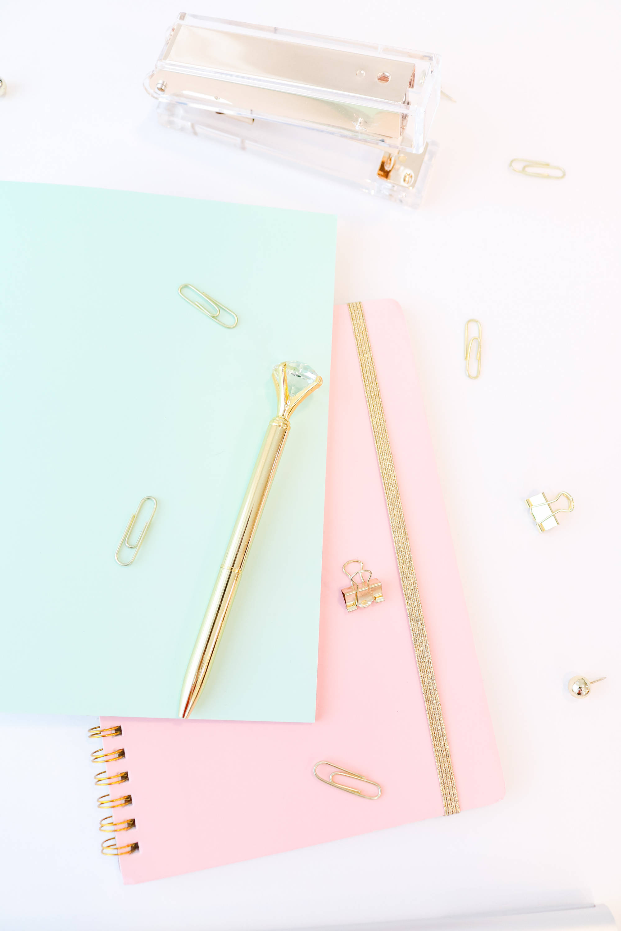 girly pink aesthetic 桌布 壁紙 — 粉彩筆記本和金色文具散落在簡約工作空間的明亮白色桌子上。