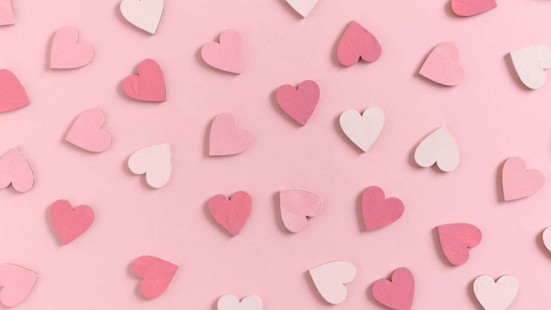 Pink Love 桌布 壁紙 — 粉彩粉紅色木製心形散落在柔和的粉紅色背景上，形成平鋪構圖。