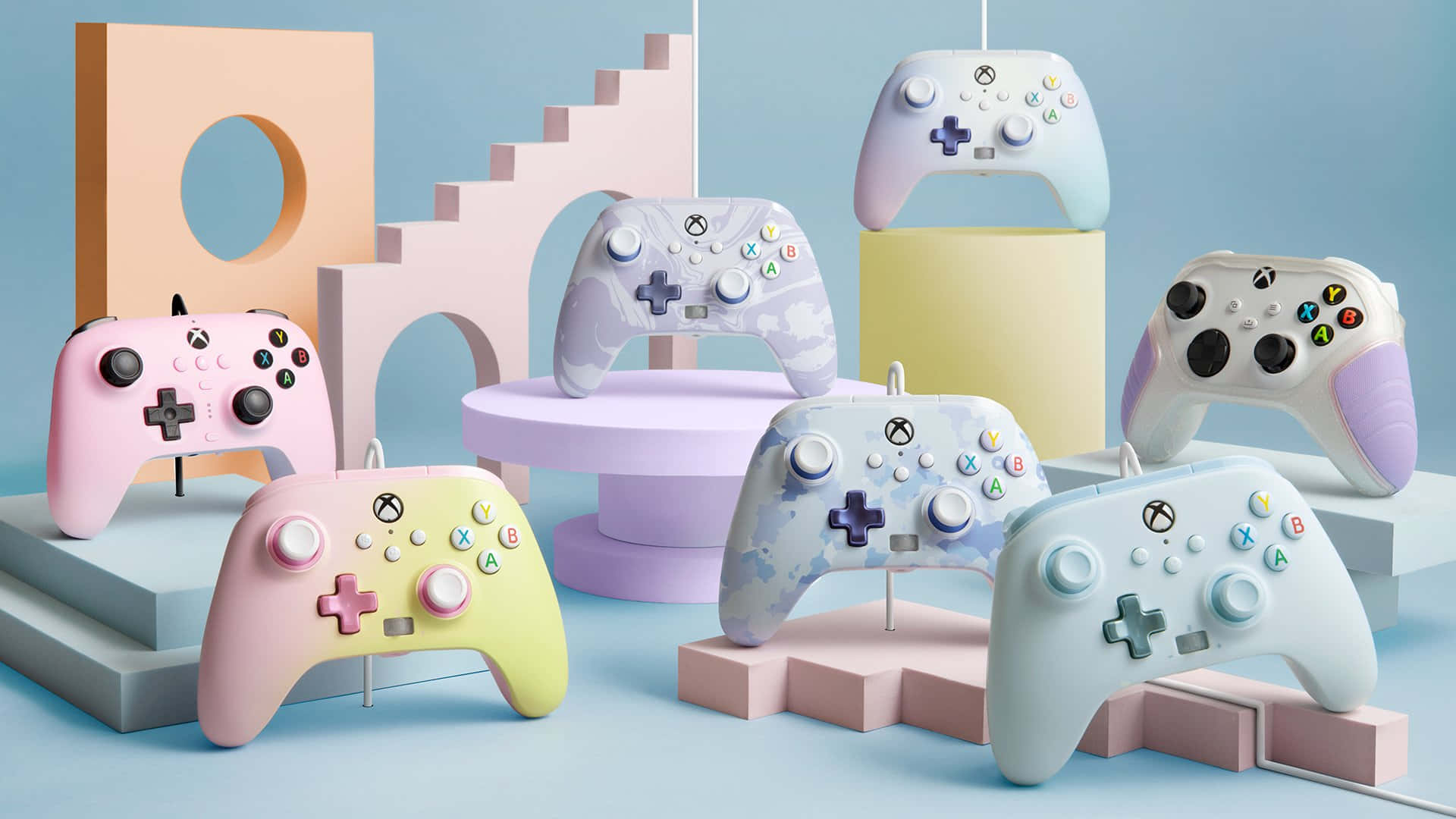 Xbox 桌布 壁紙 — 粉彩色Xbox手把展示在幾何支架上，背景為柔和藍色。