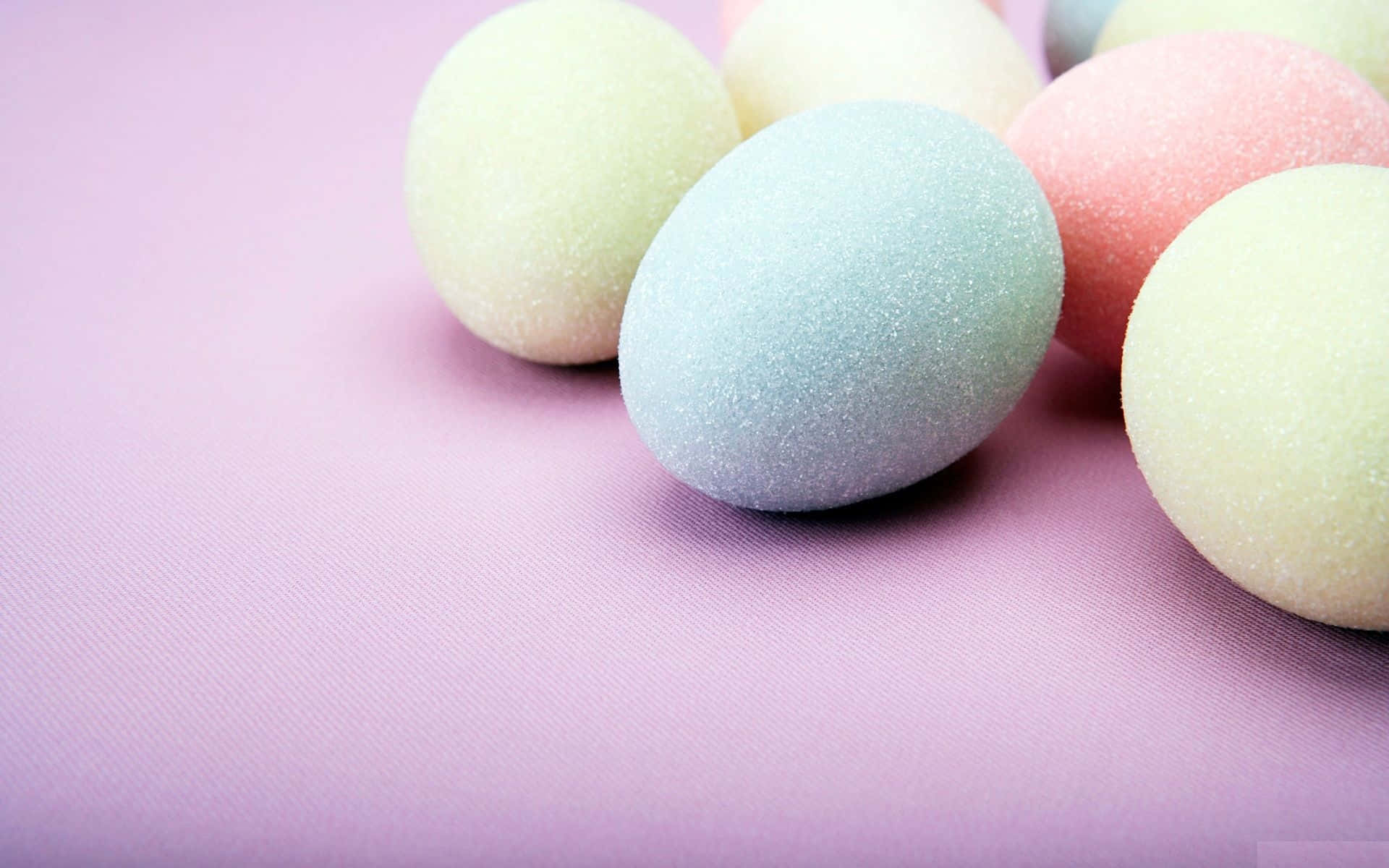 Pastel Easter 桌布 壁紙 — 粉彩色糖蛋輕輕放在有紋理的薰衣草色表面上，以淺景深拍攝。