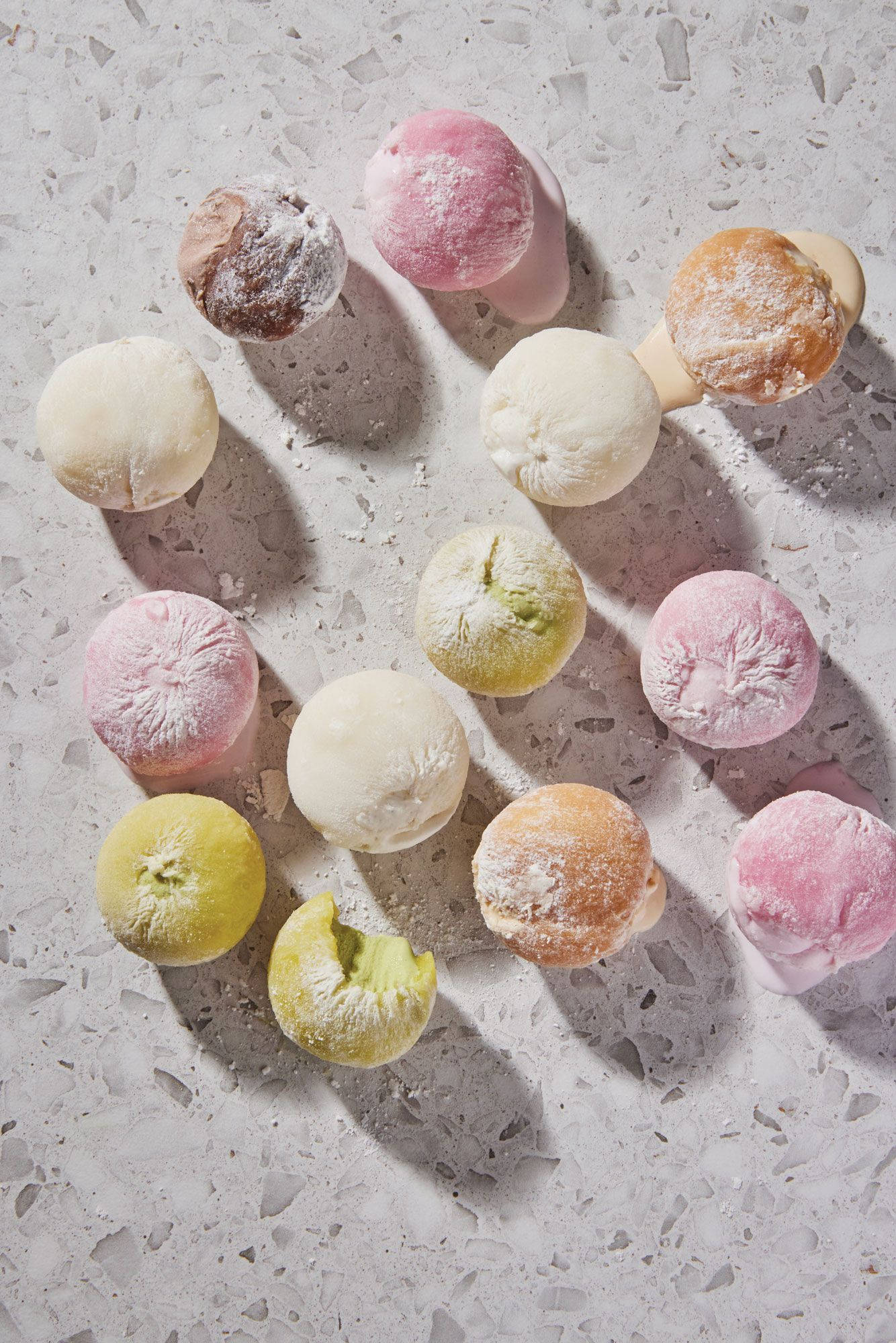 Mochi 桌布 壁紙 — 粉彩色麻糬球撒上糖粉，放在有斑點的灰色表面上，光線明亮。