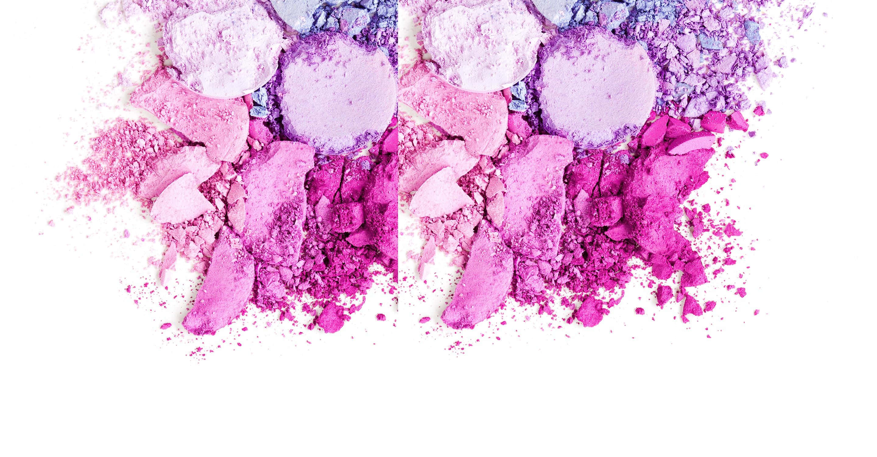 Mac Cosmetics 桌布 壁紙 — 粉碎的粉紅色和紫色眼影盤在潔白背景上散落，形成充滿活力的爆炸效果。