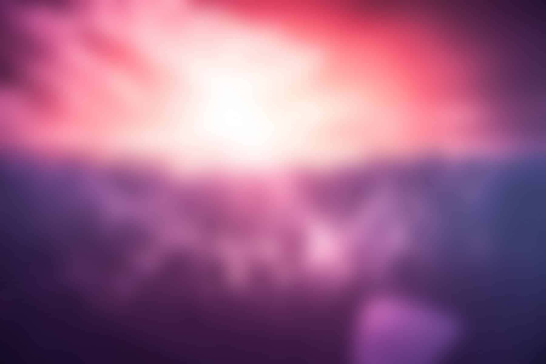 Blurry 桌布 壁紙 — 粉紅、紫色和藍色的柔和模糊漸變，中心明亮發光，營造出夢幻般的日落或日出氛圍。