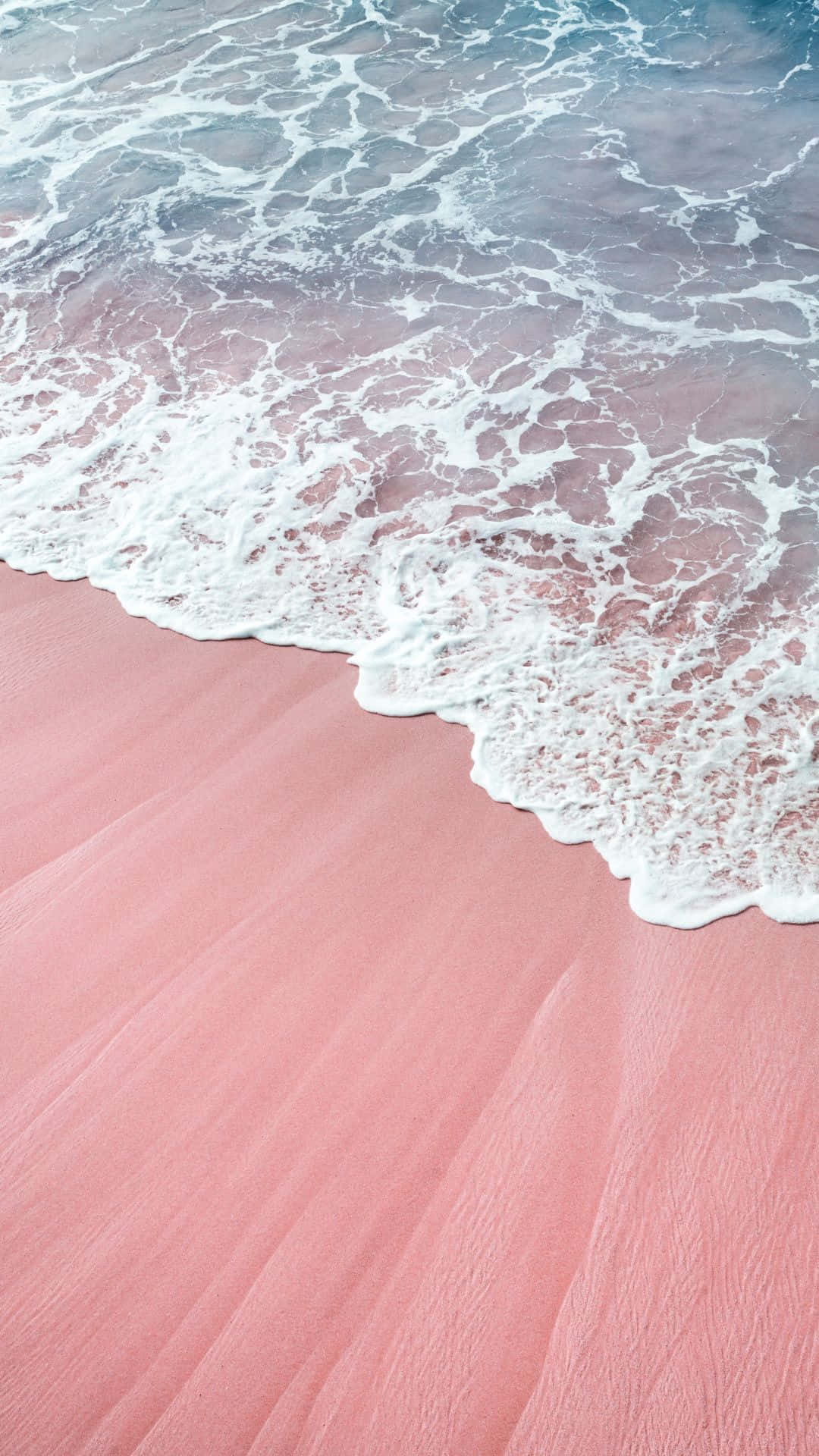 Ocean Aesthetic Phone 桌布 壁紙 — 粉紅沙灘，溫柔的海浪拍打著，在紋理豐富的海岸線上形成白色泡沫。