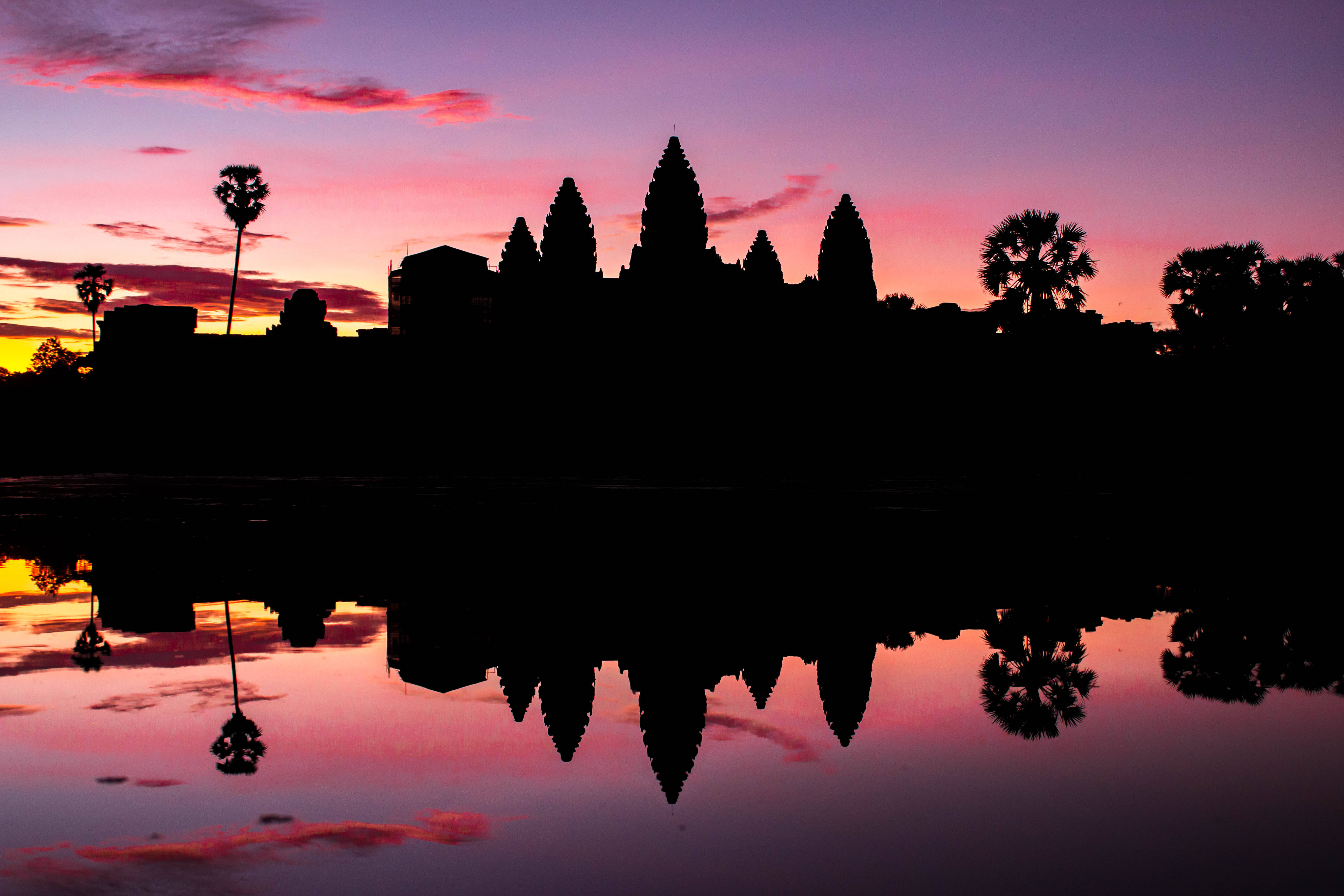 Cambodia 桌布 壁紙 — 粉紅紫色天空下，吳哥窟寺廟群在日落時分的剪影，平靜水面完美倒映。