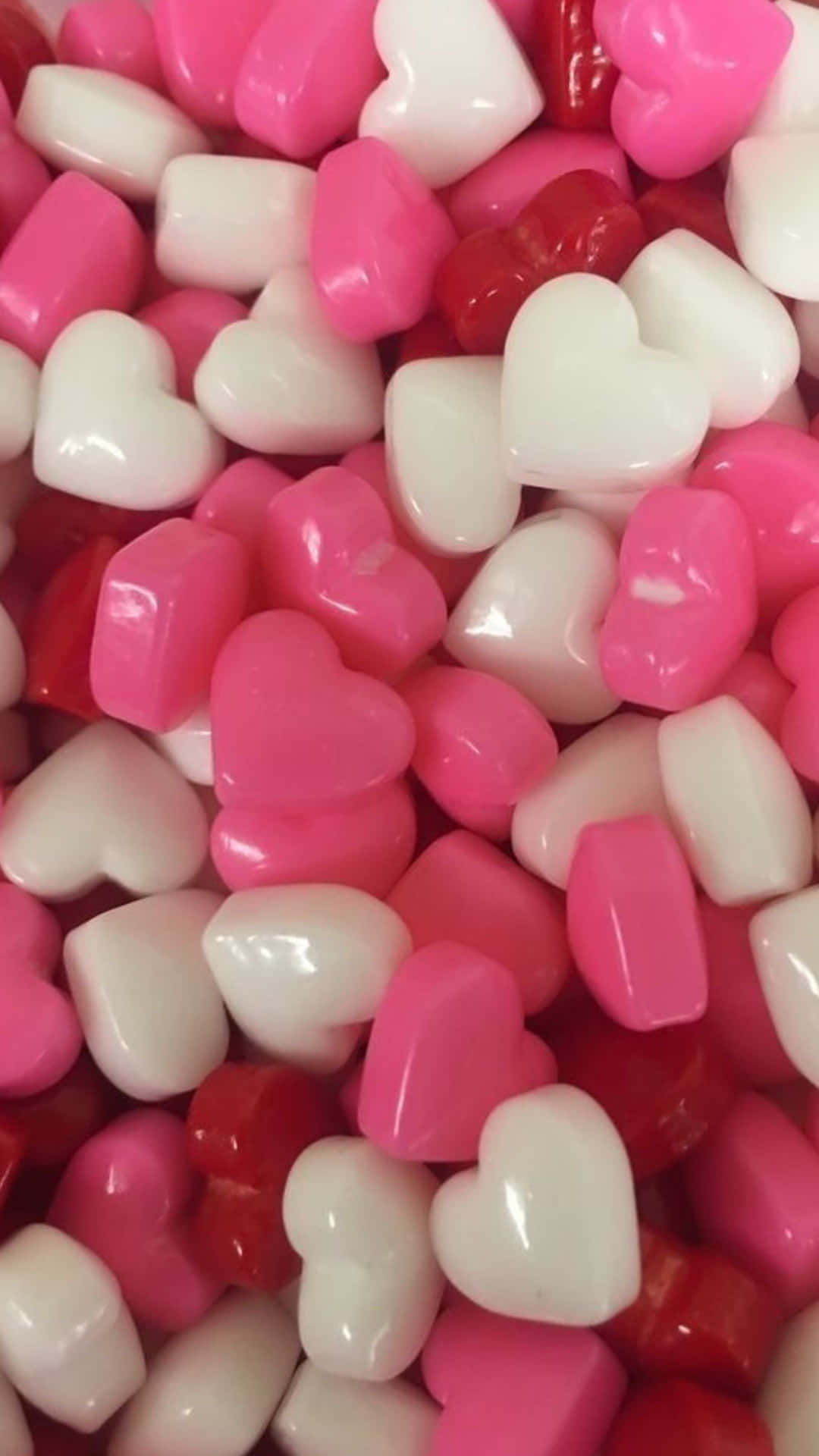 Red Hearts 桌布 壁紙 — 粉紅色、白色和紅色的光澤心形糖果堆疊在一起的近距離特寫。