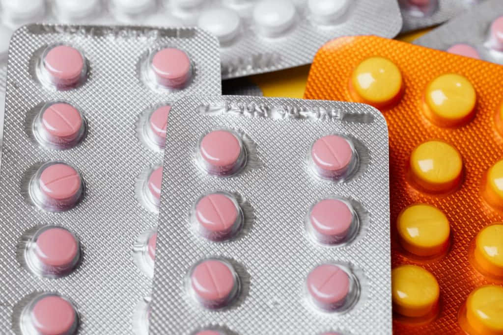 pills 桌布 壁紙 — 粉紅色和黃色藥丸在泡罩包裝中的特寫，背景為金屬箔。