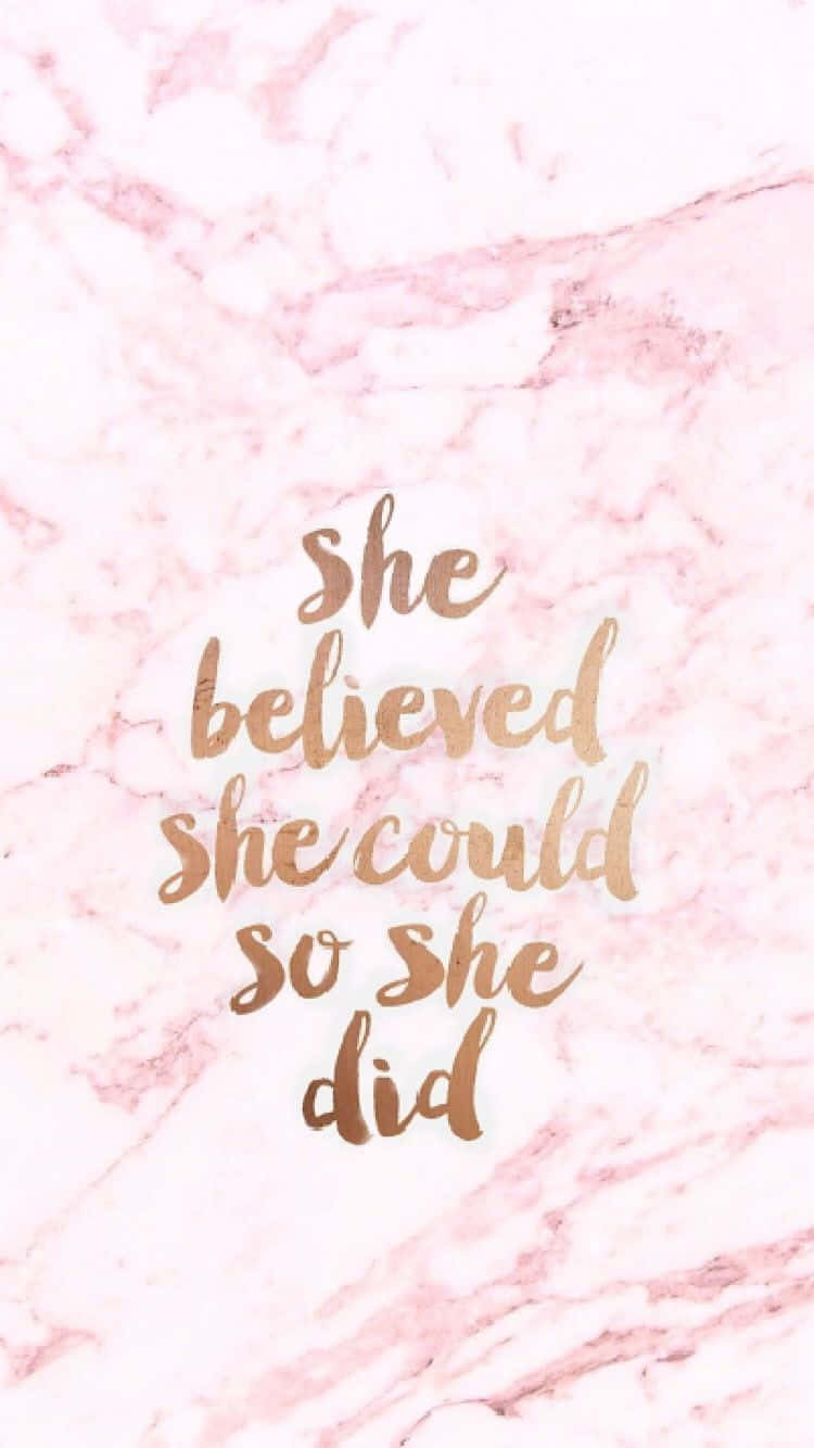 Quote 桌布 壁紙 — 粉紅色大理石背景，金色草書文字寫著「she believed she could so she did」，用於勵志桌布。