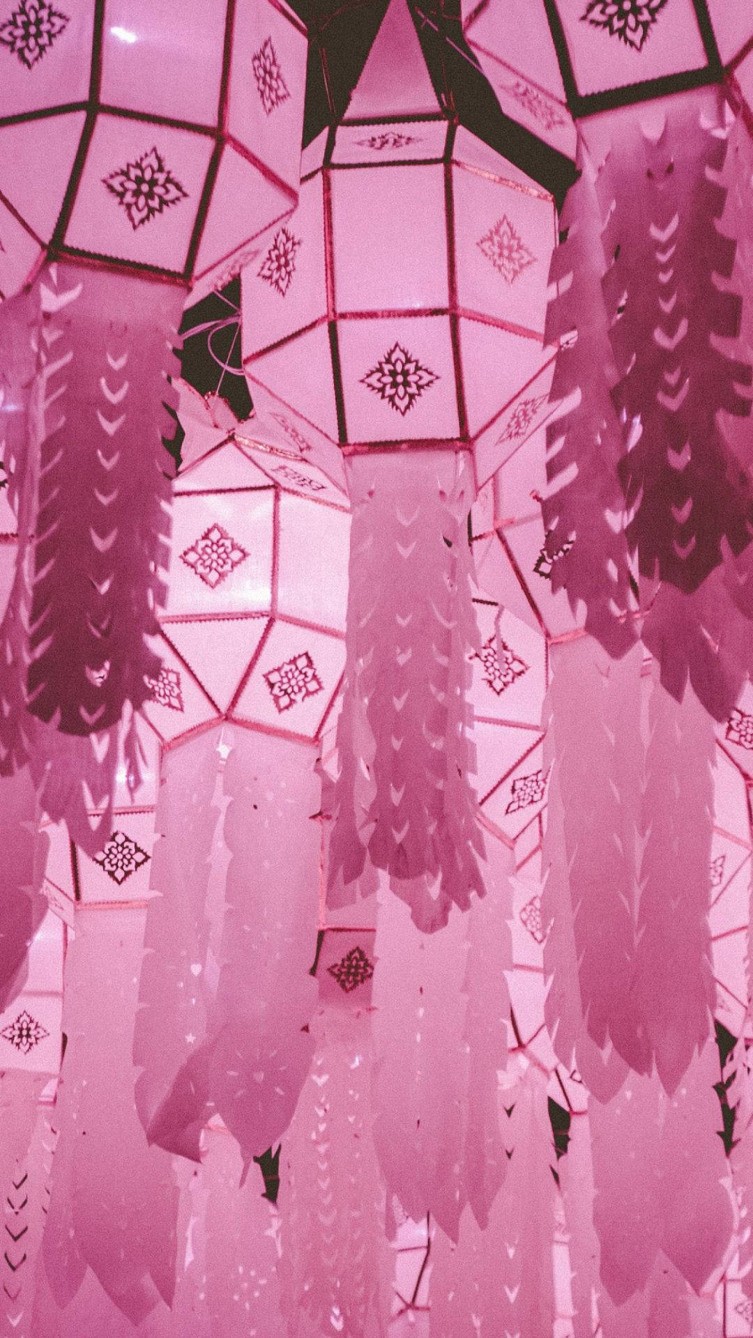 美學粉色GIF 桌布 壁紙 — 粉紅色幾何燈籠帶有精緻圖案，懸掛在柔和發光的展示中。