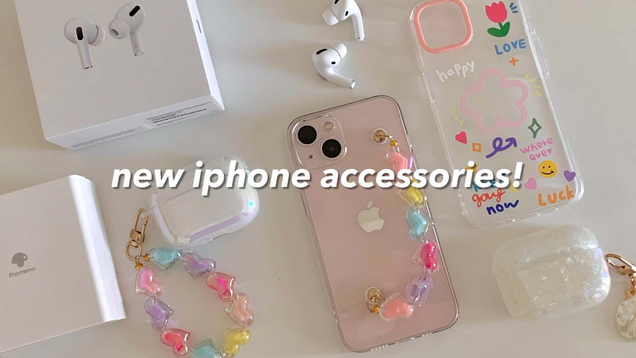 可愛 iPhone 桌布 桌布 壁紙 — 粉紅色手機上包括AirPods和彩色心形吊飾保護殼在內的新iPhone配件平鋪圖。