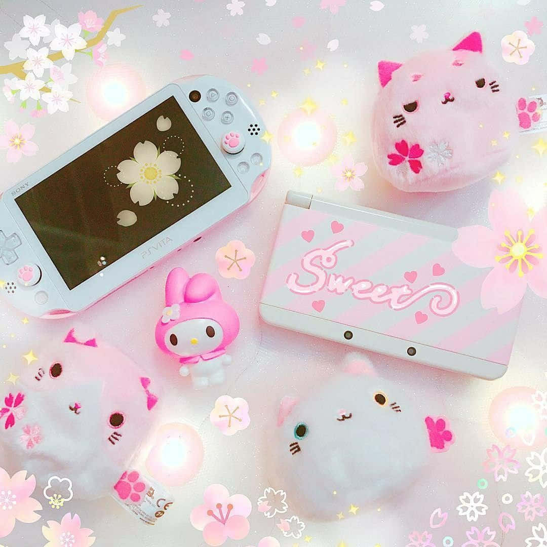 Kawaii Gaming 桌布 壁紙 — 粉紅色柔和遊戲設置，配有絨毛貓咪和櫻花，在手提遊戲機周圍柔和發光。