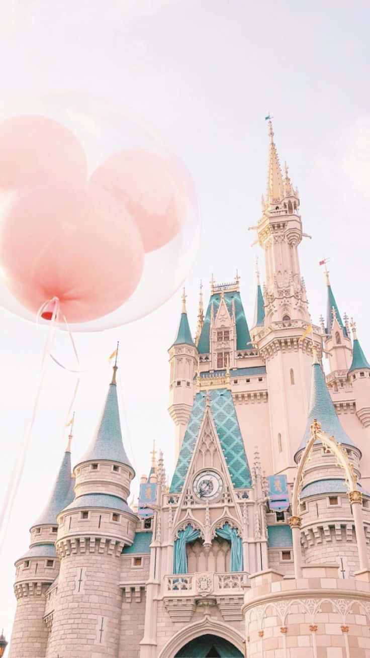 Disneyland Castle 桌布 壁紙 — 粉紅色氣球在柔和天空下飄浮在帶有青綠色尖頂的童話城堡前。