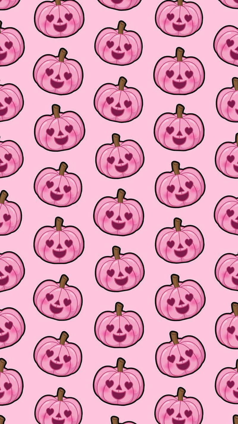 Pink Halloween 桌布 壁紙 — 粉紅色的南瓜帶有心形眼睛，在柔和的粉紅色背景上以重複圖案微笑。