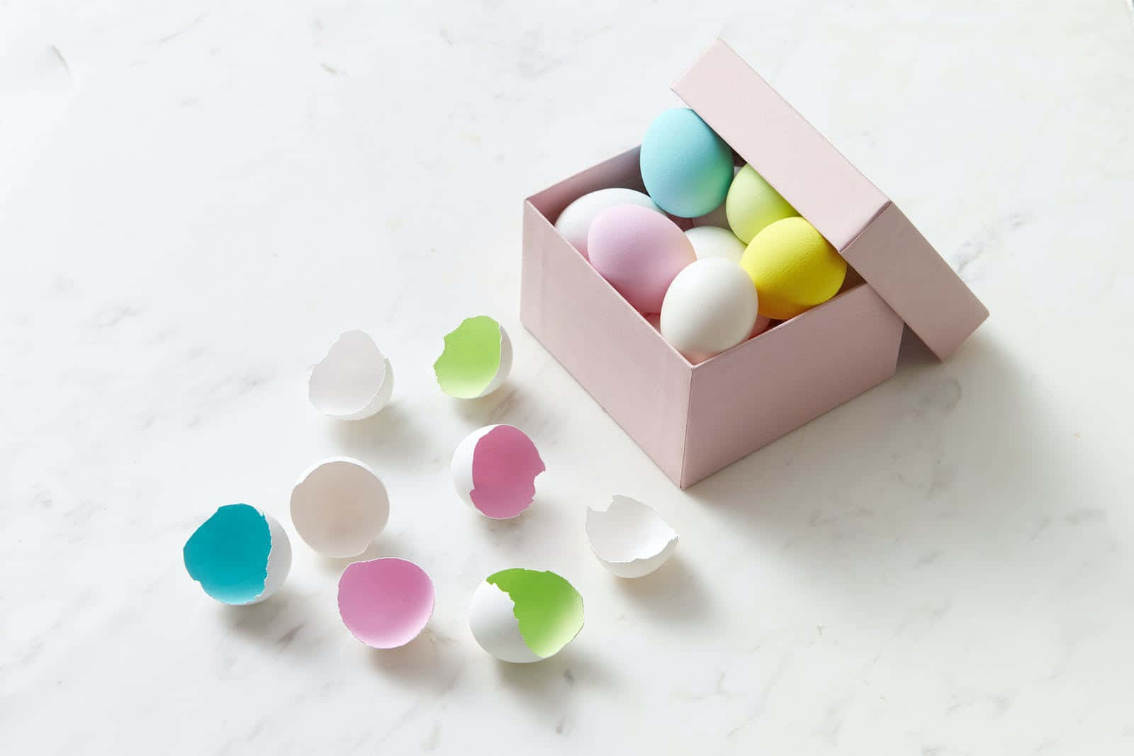 Happy Easter 桌布 壁紙 — 粉紅色盒子裡裝著粉彩色的蛋，白色大理石表面上散落著鮮豔的蛋殼。