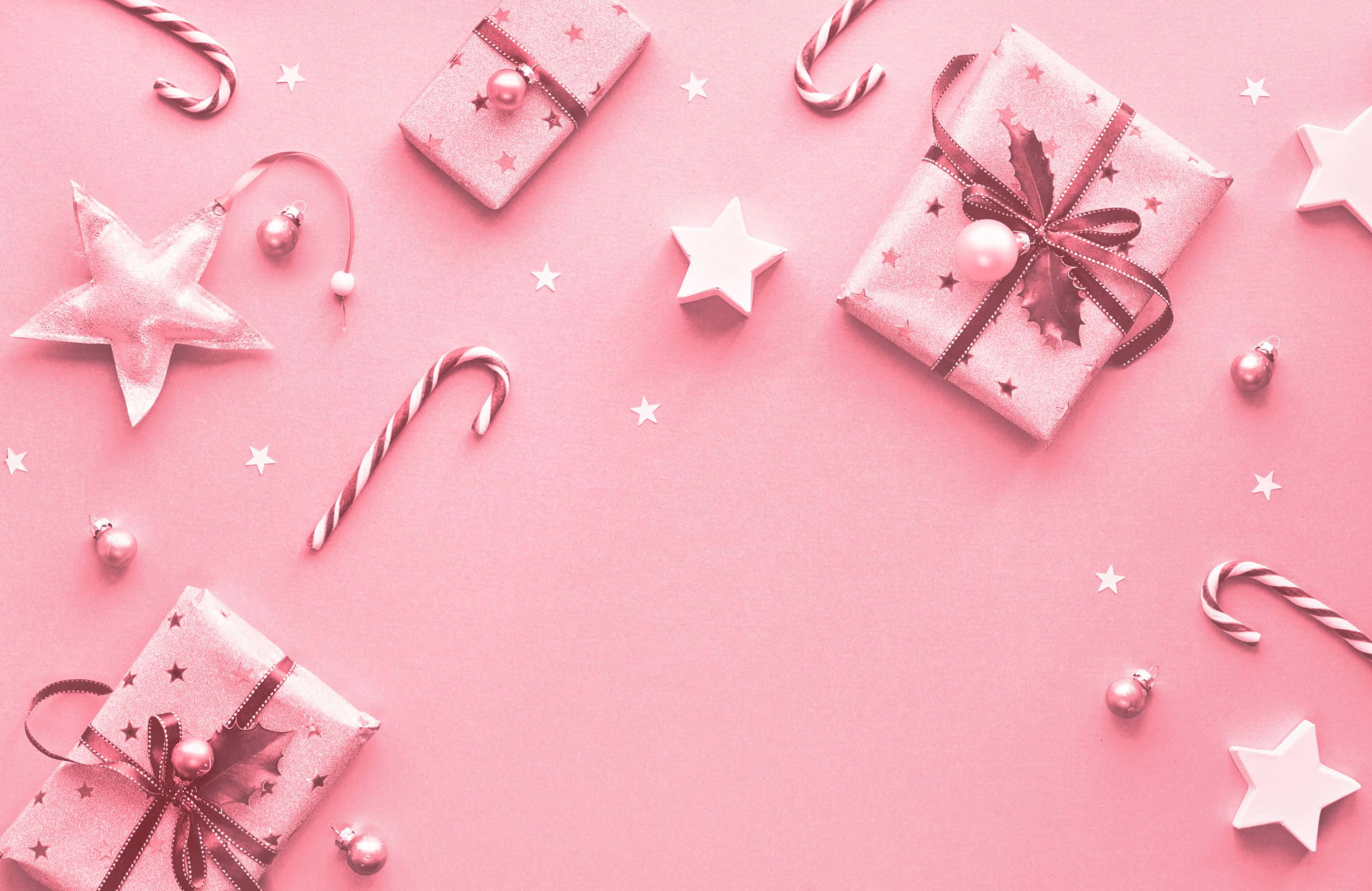 pink christmas 桌布 壁紙 — 粉紅色節日禮物、拐杖糖和星星排列在柔和的粉紅色背景上，營造節日慶祝氣氛。
