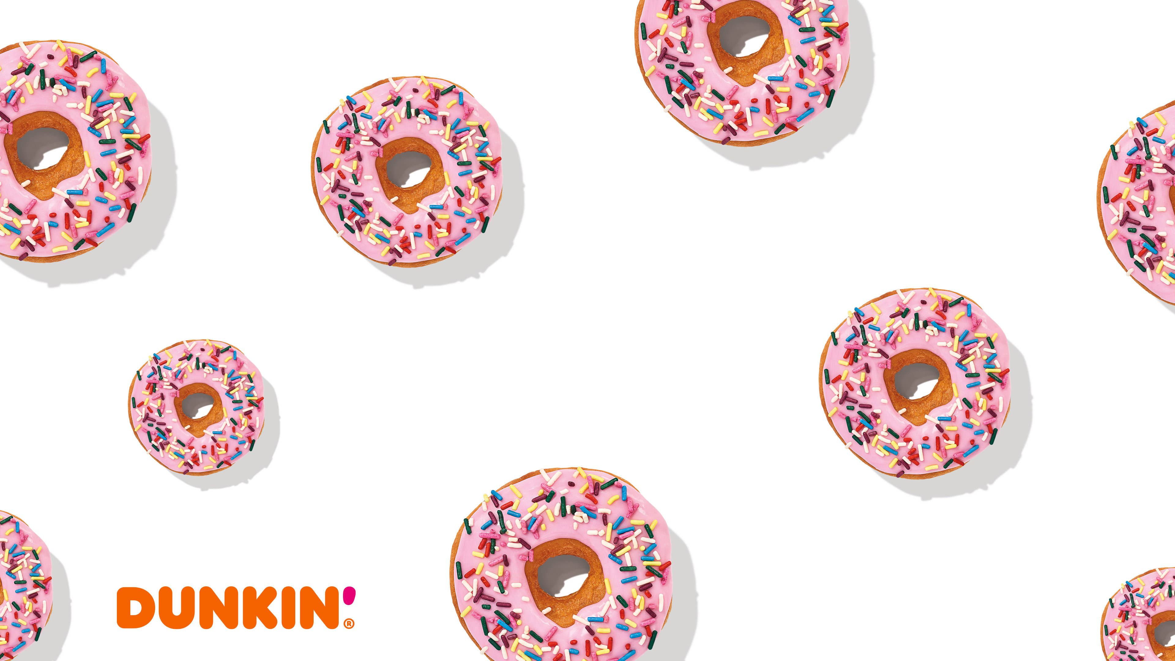 donuts 桌布 壁紙 — 粉紅色糖霜甜甜圈，上面散落著彩色糖粒，放在潔白背景上，附有Dunkin'標誌。