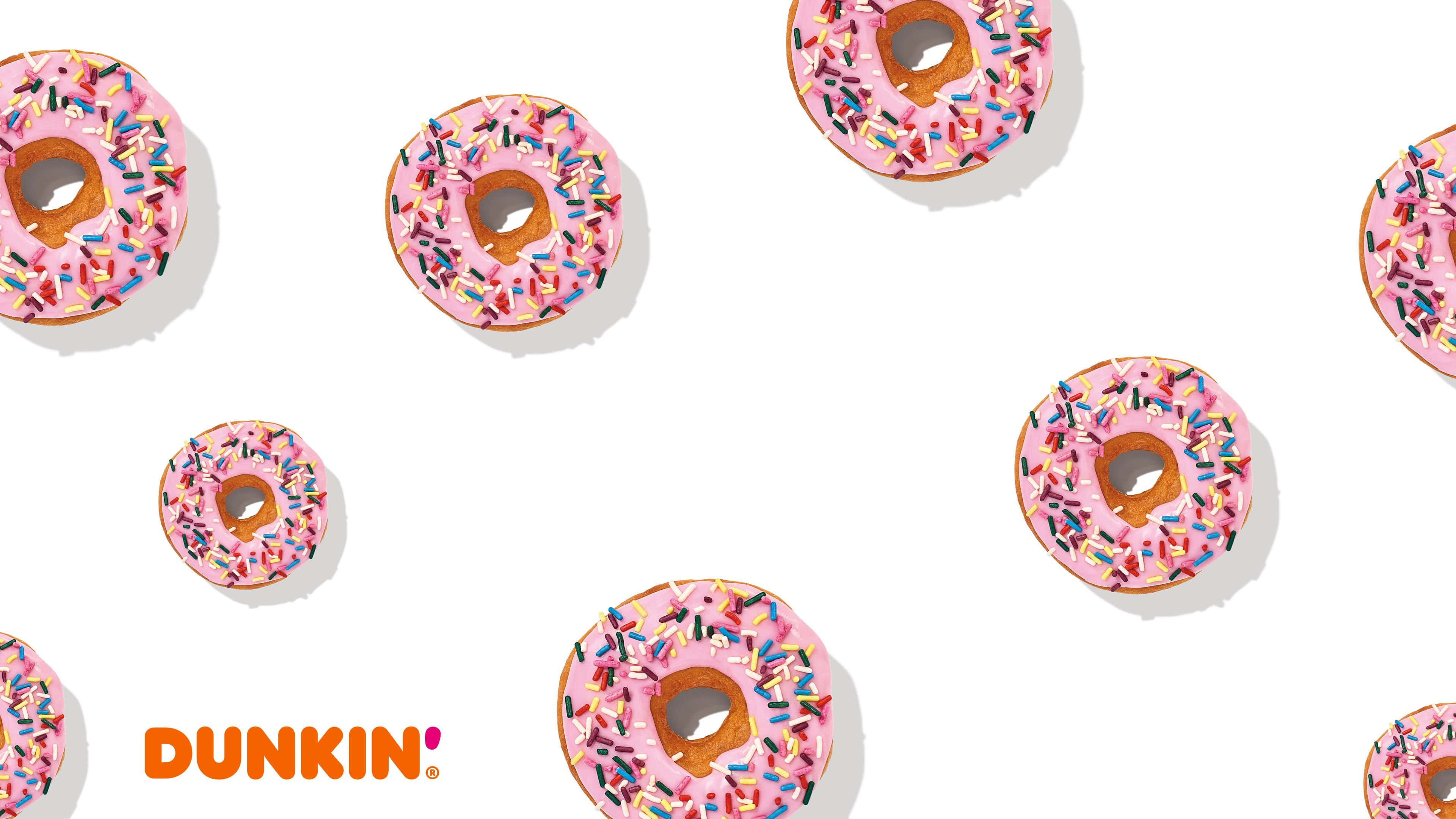Dunkin Donuts 桌布 壁紙 — 粉紅色糖霜甜甜圈，上面散落著彩色糖粒，背景為亮白色，帶有Dunkin'標誌。