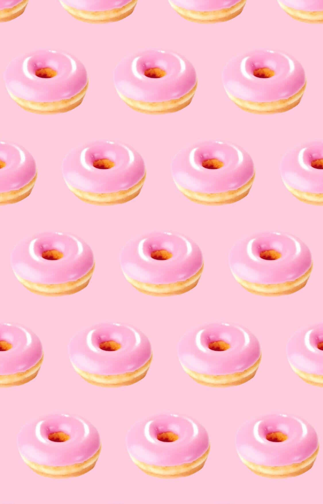 Cute Donut 桌布 壁紙 — 粉紅色糖霜甜甜圈整齊排列在柔和的粉紅色背景上。