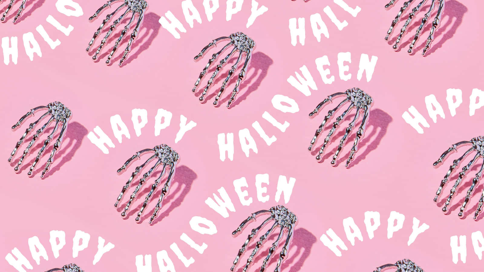 Pink Halloween 桌布 壁紙 — 粉紅色背景，重複的銀色骷髏手，以及粗體俏皮字體的白色「Happy Halloween」文字。