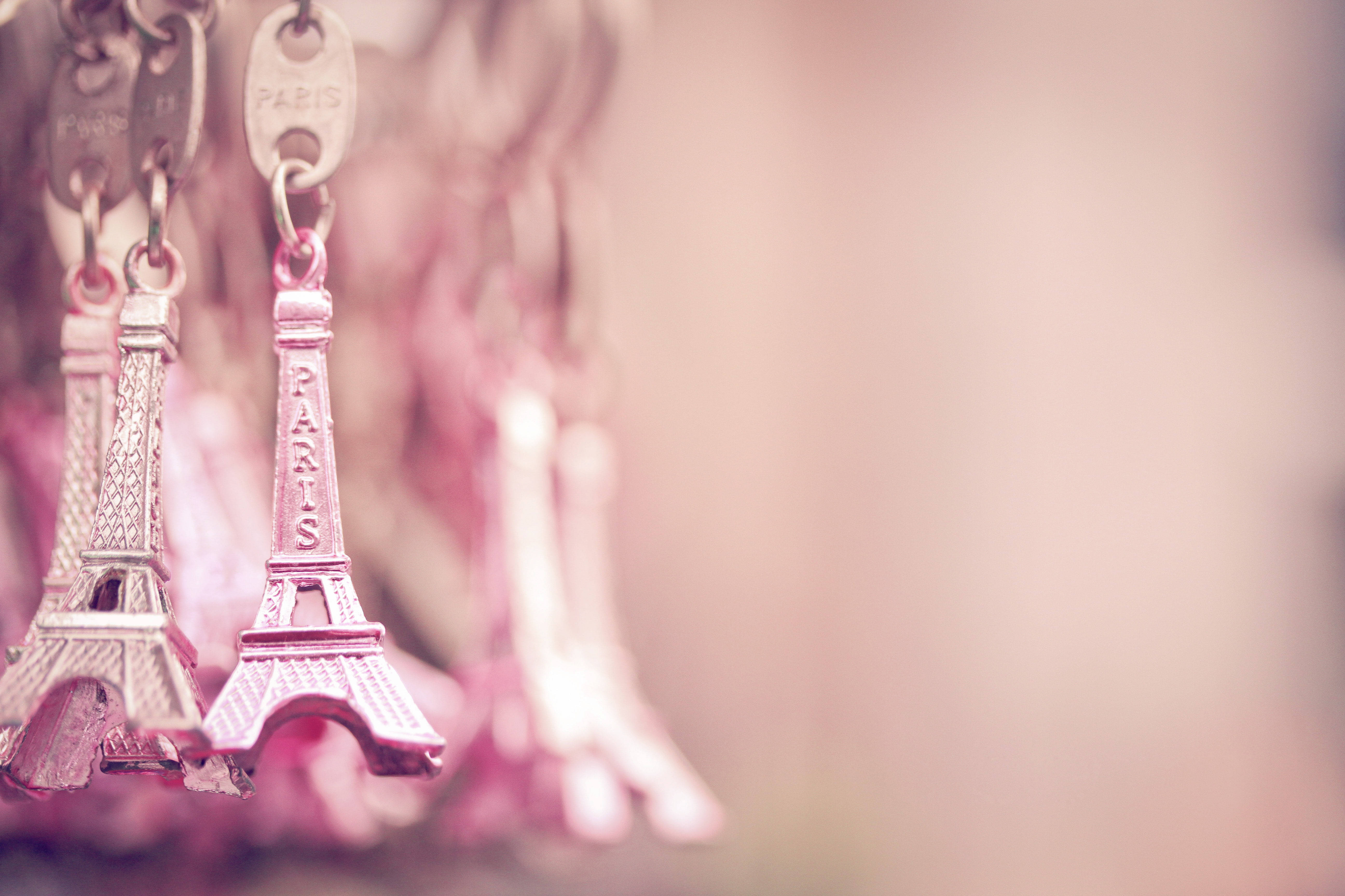 Eiffel Tower 桌布 壁紙 — 粉紅色調的微型艾菲爾鐵塔鑰匙圈，在夢幻的柔和背景上輕輕模糊地懸掛著。