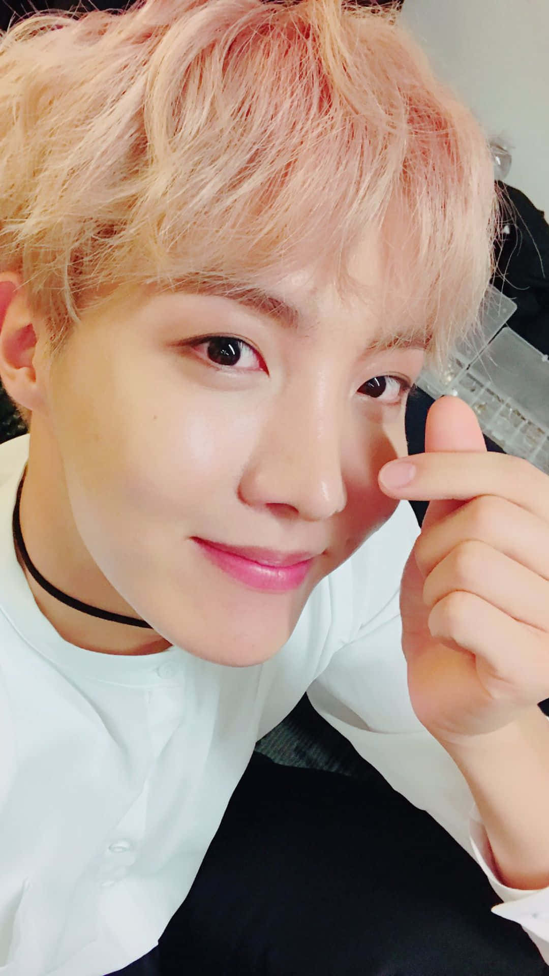 jhope 桌布 壁紙 — 粉紅色頭髮的年輕男子輕觸臉頰溫柔微笑的特寫自拍。
