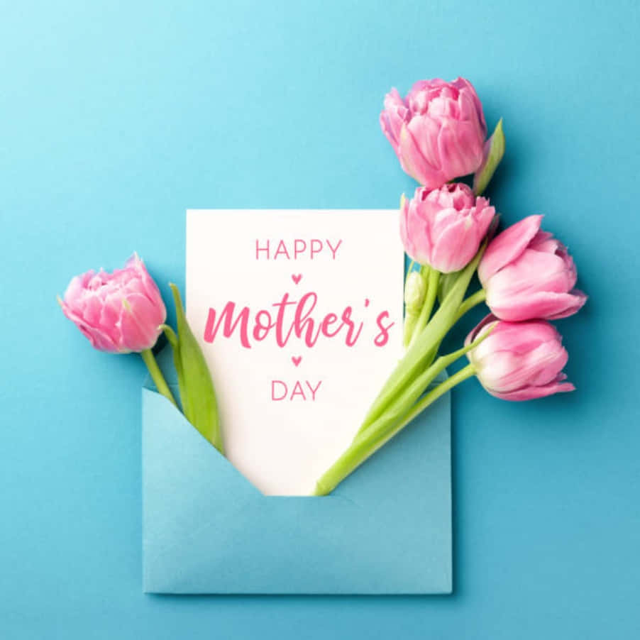 Happy Mothers Day 桌布 壁紙 — 粉紅色鬱金香從一個藍色信封中溢出，信封內有一張「Happy Mother's Day」賀卡，背景為純藍色。