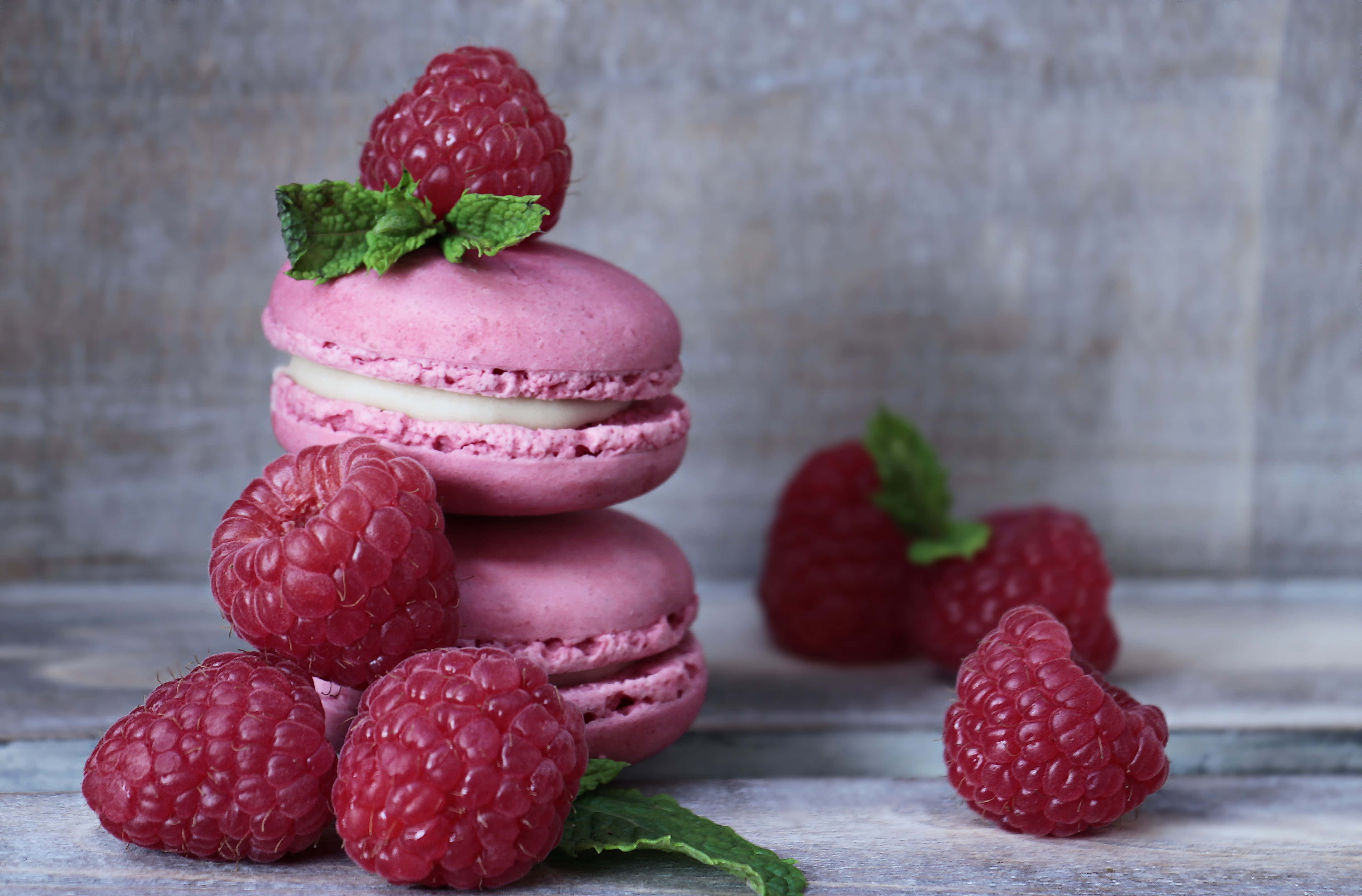 Raspberry 桌布 壁紙 — 粉紅覆盆子馬卡龍堆疊，配上新鮮莓果和薄荷葉，放在質樸的木質表面上。