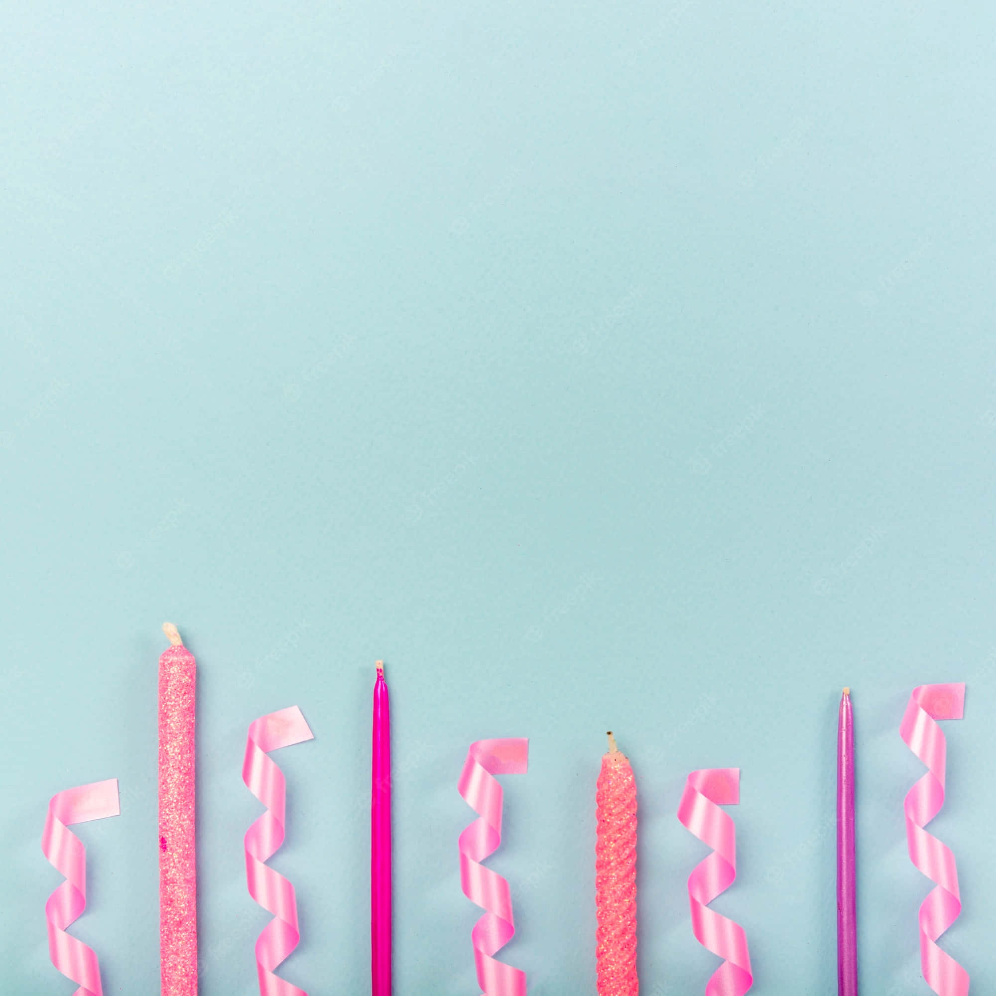 Quinceanera 桌布 壁紙 — 粉紅閃粉和實心蠟燭搭配螺旋絲帶整齊排列在柔和的藍色背景上。