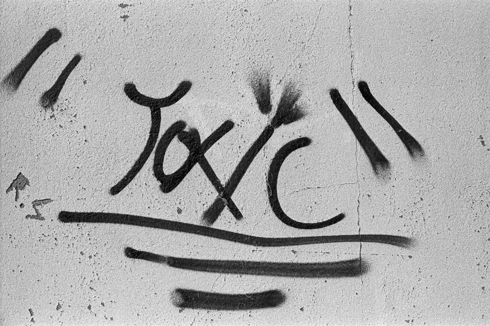 混凝土牆上黑色塗鴉字 toxic。 — 塗鴉 GIF 壁紙
