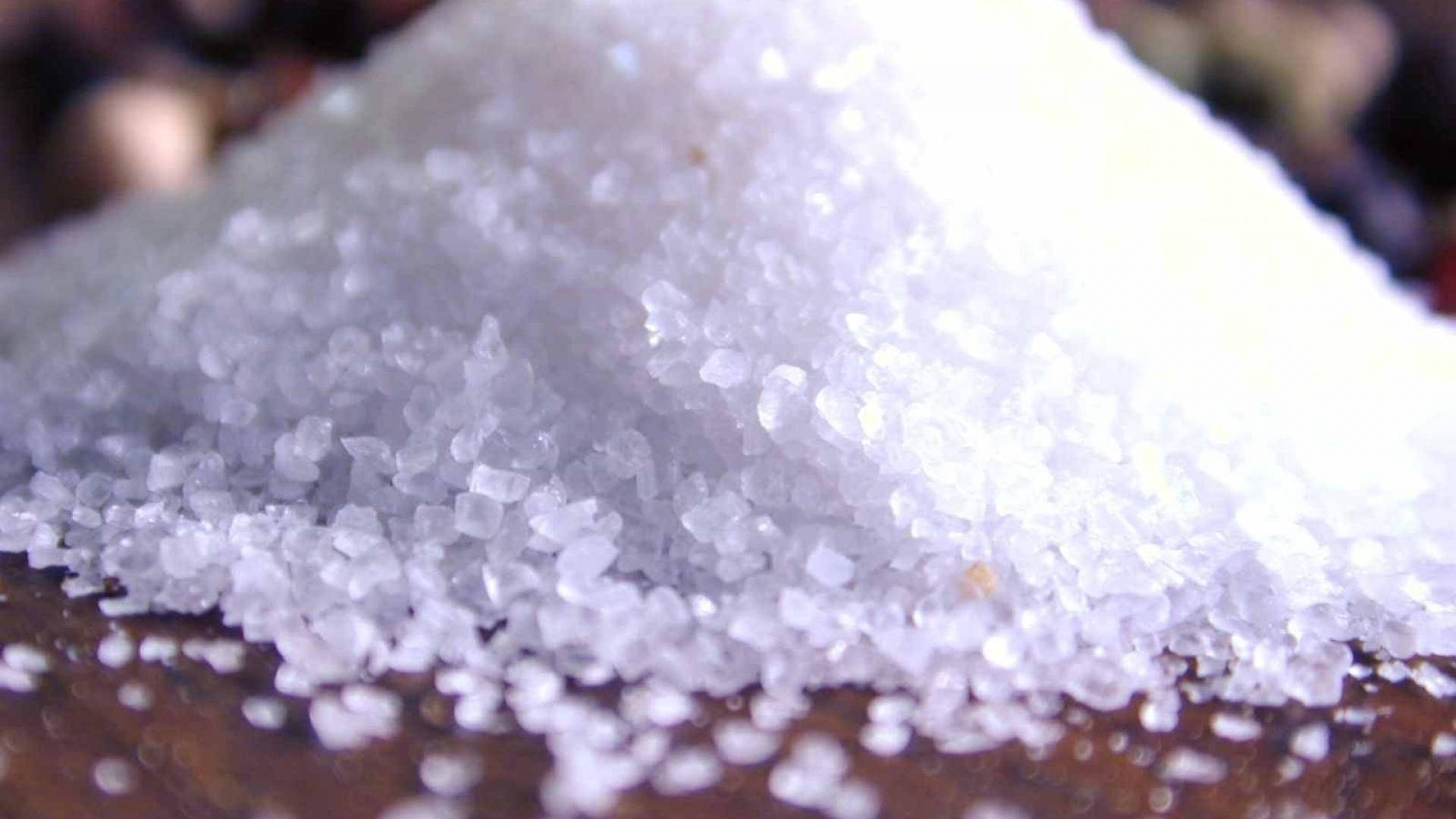 Sugar 桌布 壁紙 — 粗白鹽結晶的特寫，高高堆在深色木質表面上，背景柔和散景。