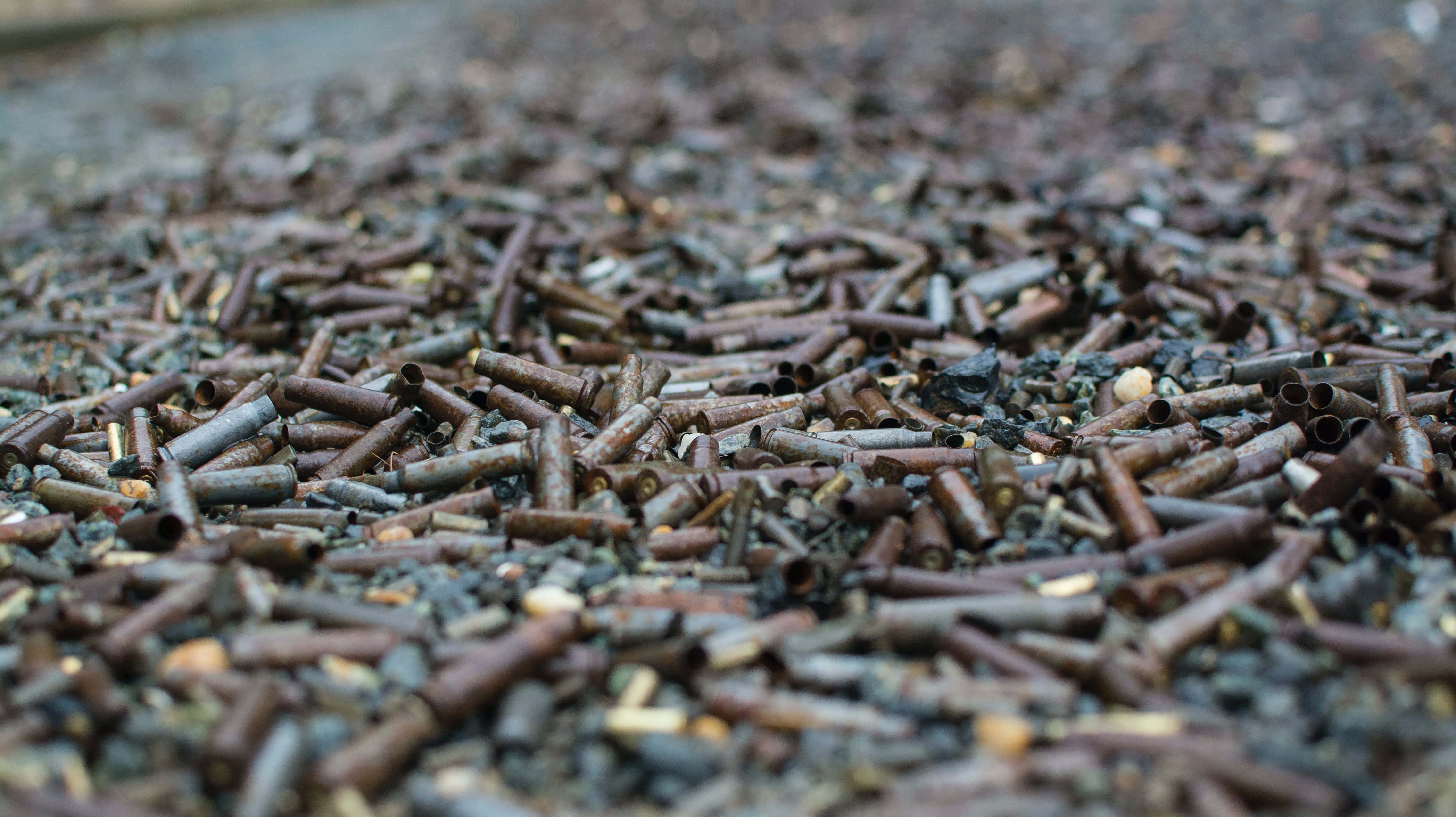 bullet 桌布 壁紙 — 粗糙地面上散落的生鏽子彈殼和碎片的特寫。
