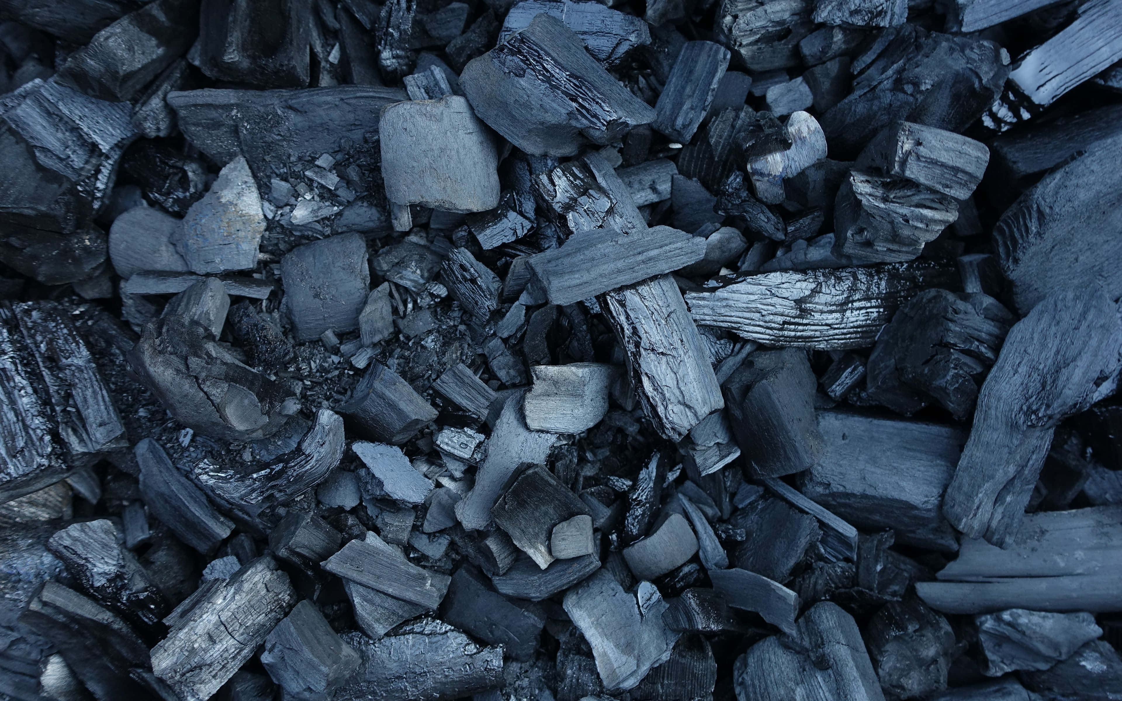 Charcoal 桌布 壁紙 — 粗糙木炭碎片的特寫，帶有冷色調的藍色和灰色，表面有紋理且邊緣鋒利。